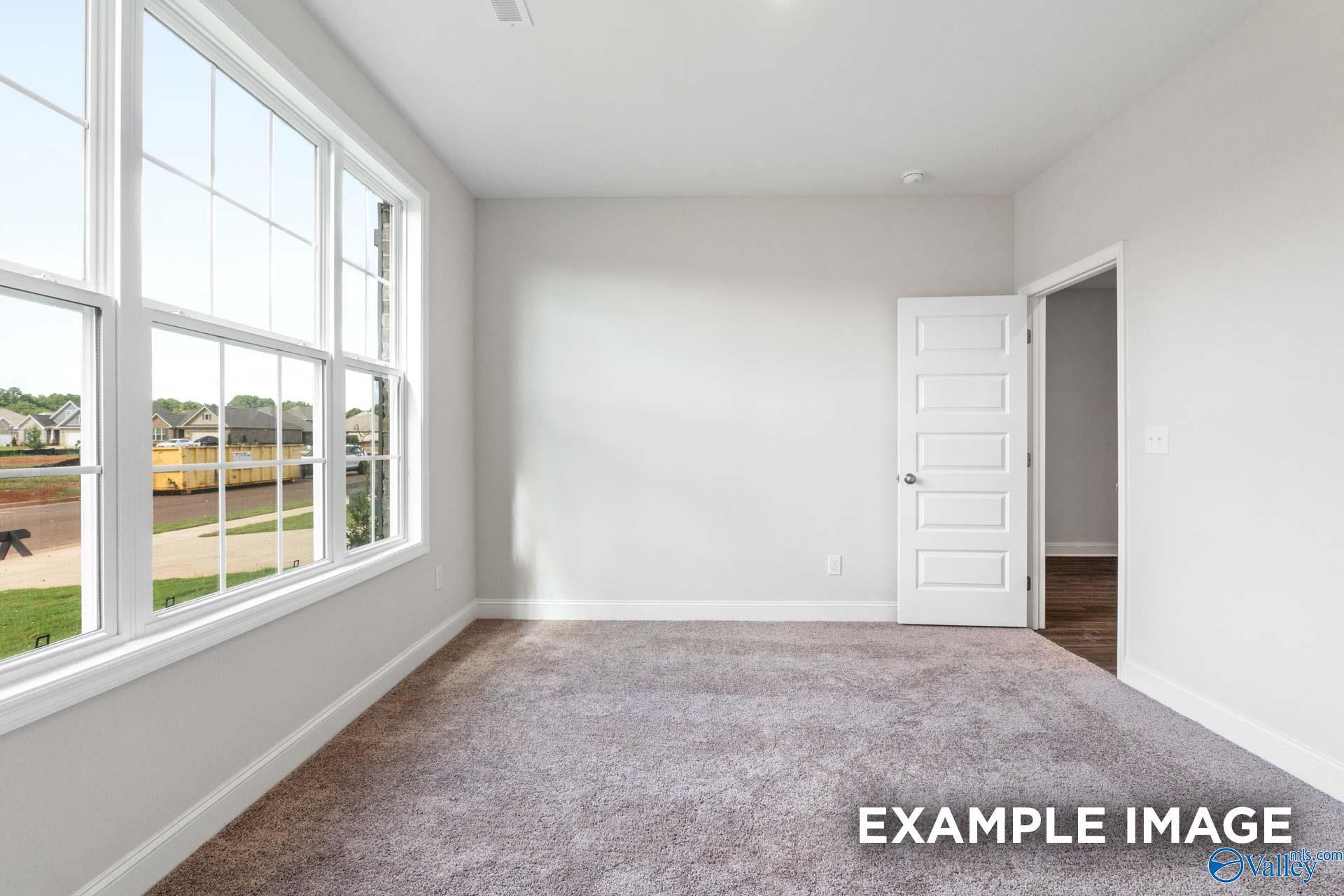 Bright living room with large windows, gray carpet, and neighborhood view in The Montgomery floor plan, Athens, Alabama