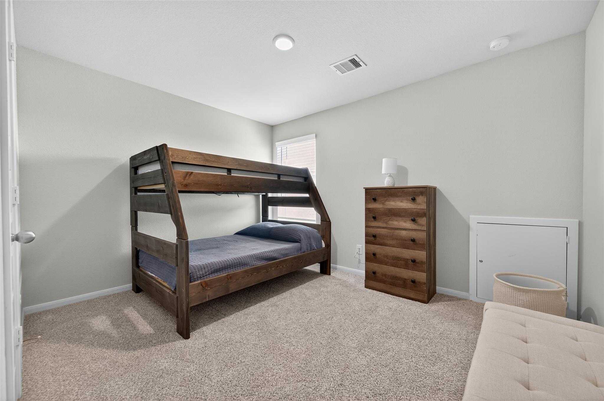 Cozy child's bedroom featuring wooden A-frame bunk beds, blue bedding, and matching dresser in 5-bedroom Davidson Homes The Brazos E, Magnolia, Texas