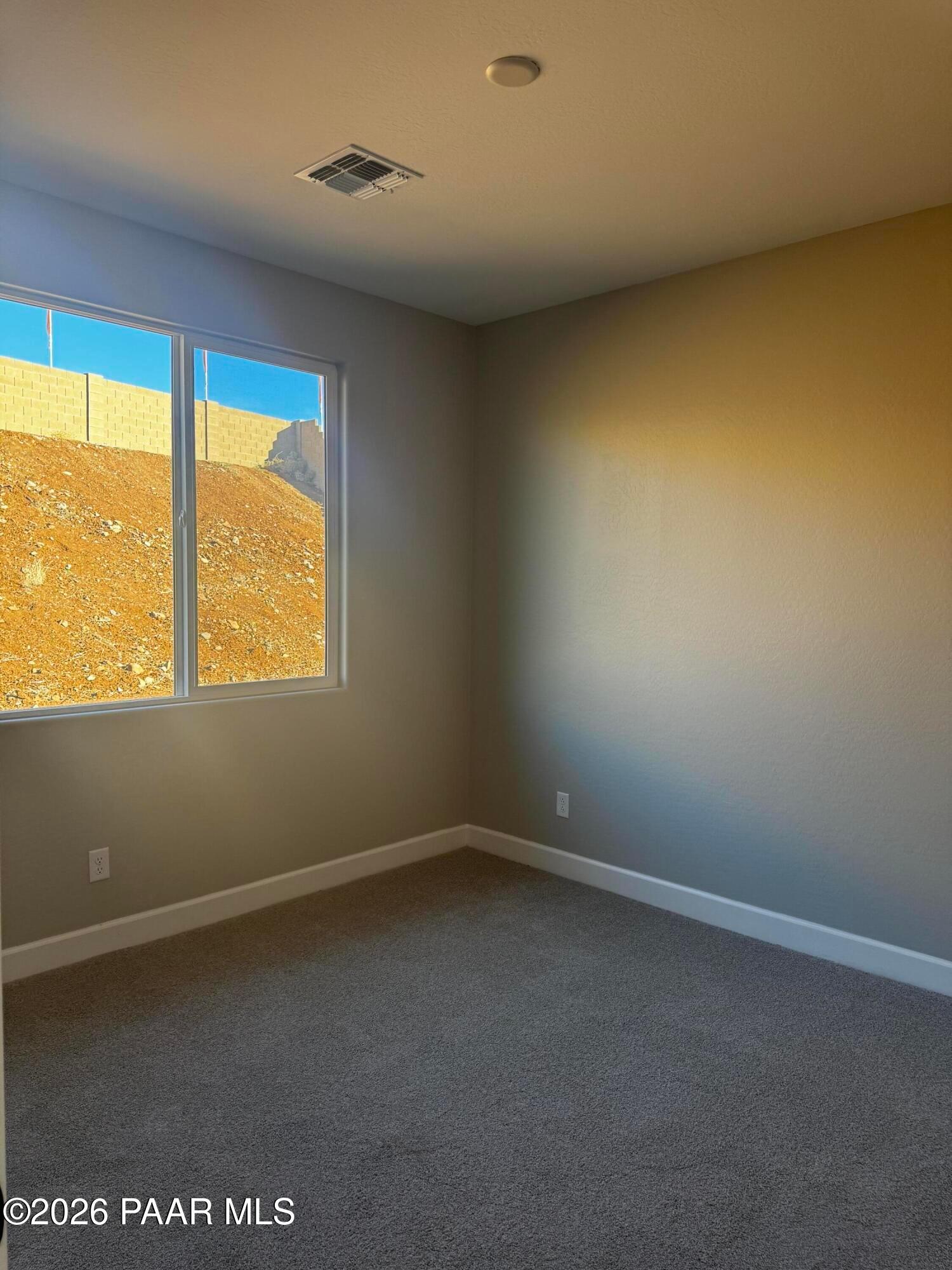 Empty bedroom with large window showcasing hillside view in The Monarch B by Evermore Homes, Prescott Valley, Arizona