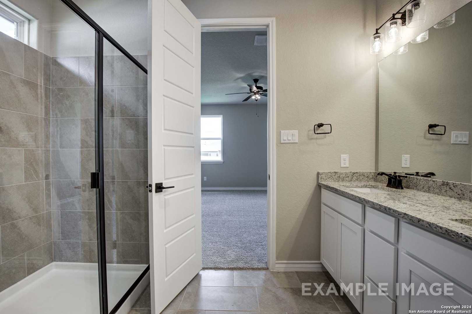 Modern master bathroom with frameless glass shower, double quartz vanity, and open door to bedroom in Davidson Homes The Rockford G, Ladera, San Antonio