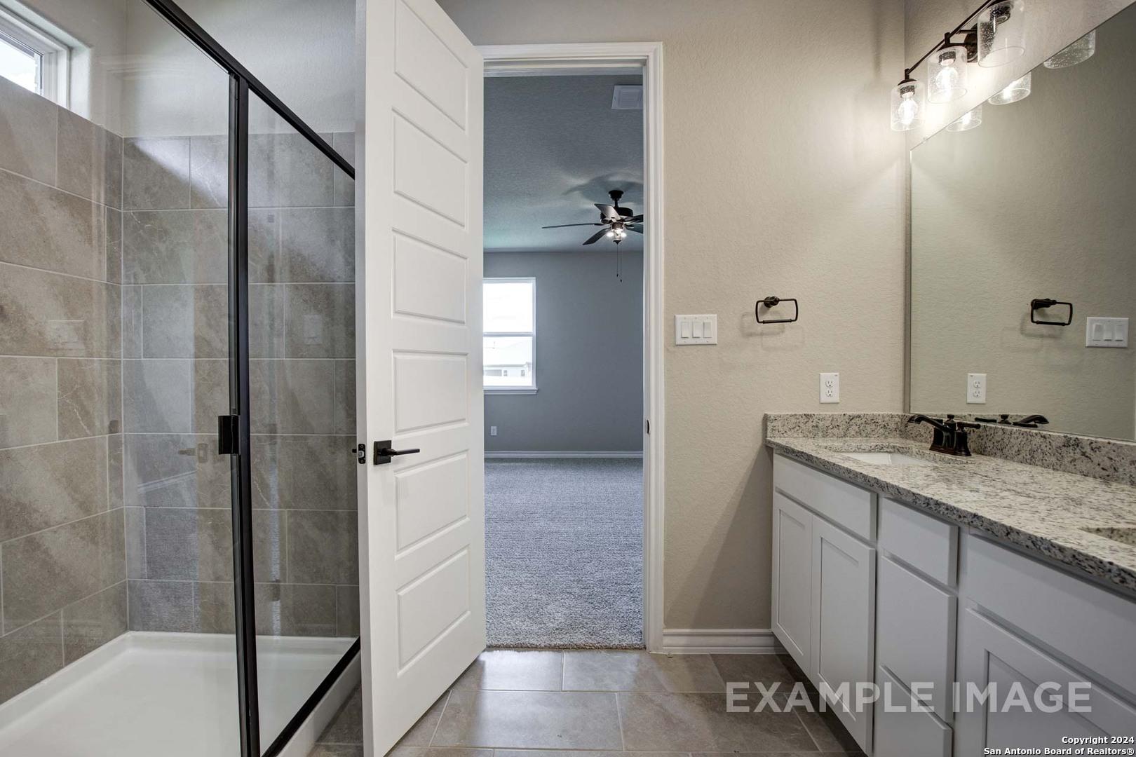 Modern master bathroom with frameless glass shower, double quartz vanity, and open door to bedroom in Davidson Homes The Rockford G, Ladera, San Antonio