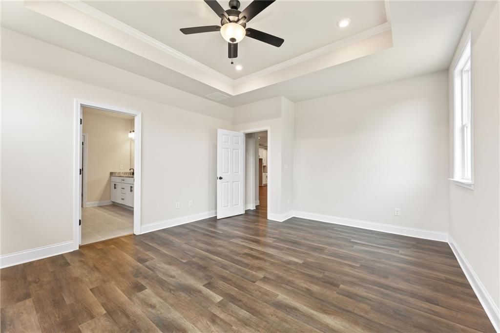 Master bedroom with tray ceiling, ceiling fan, hardwood floors, and en-suite bath featuring double vanity in Davidson Homes The Harrison H, Winder, GA