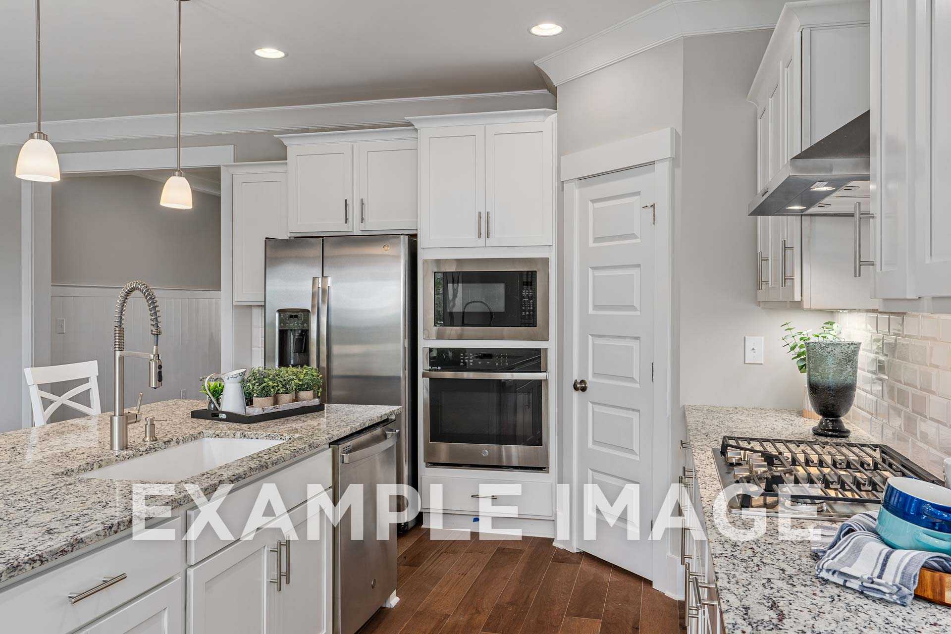 Spacious kitchen in The Harrison by Davidson Homes featuring white shaker cabinets, granite island, stainless steel appliances