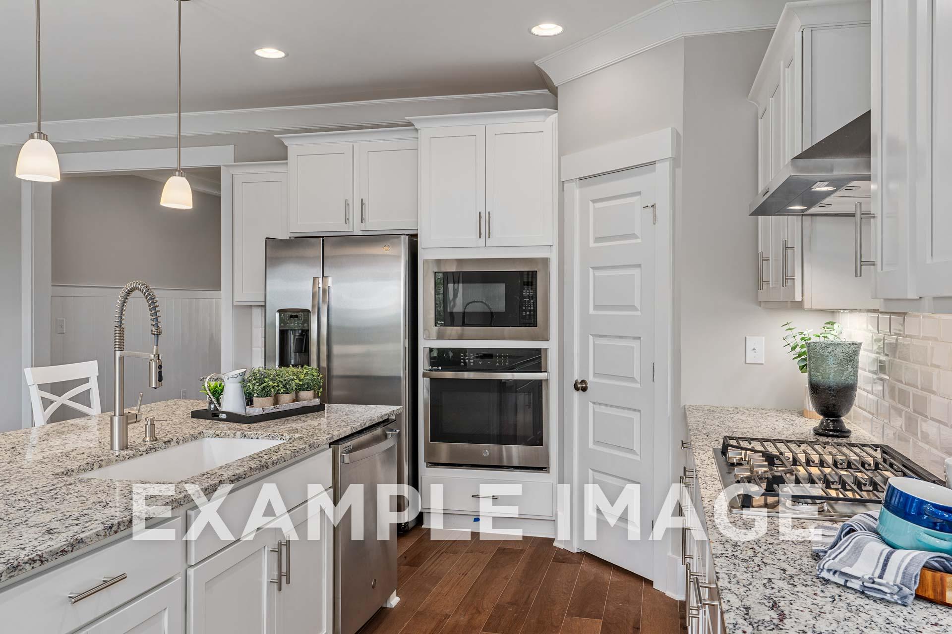 Spacious gourmet kitchen in The Harrison B featuring white cabinets, stainless steel appliances, granite island, and open layout