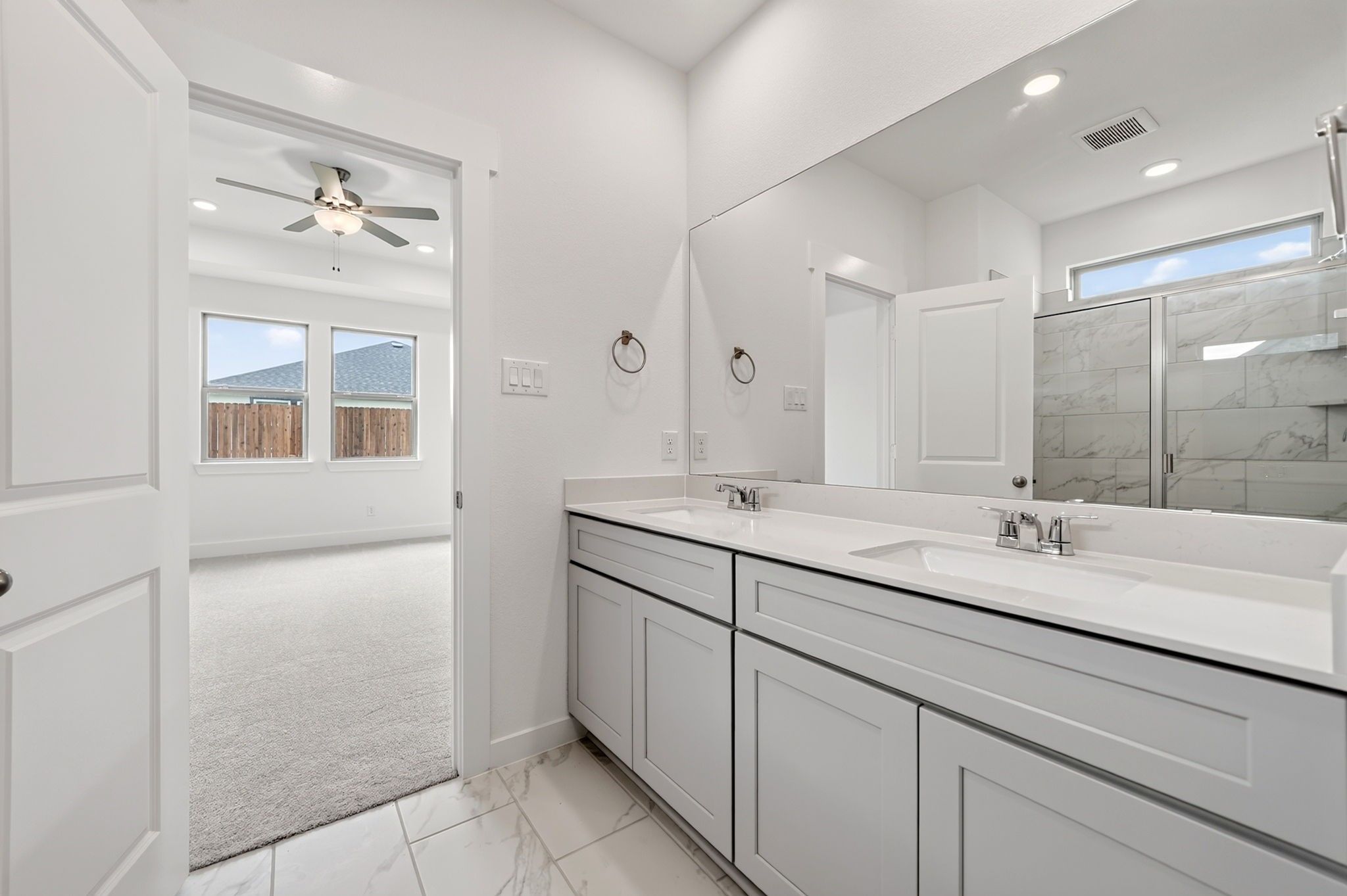 Primary bathroom with double vanity and walk-in view to carpeted bedroom in The Holly F plan, Josephine, Texas