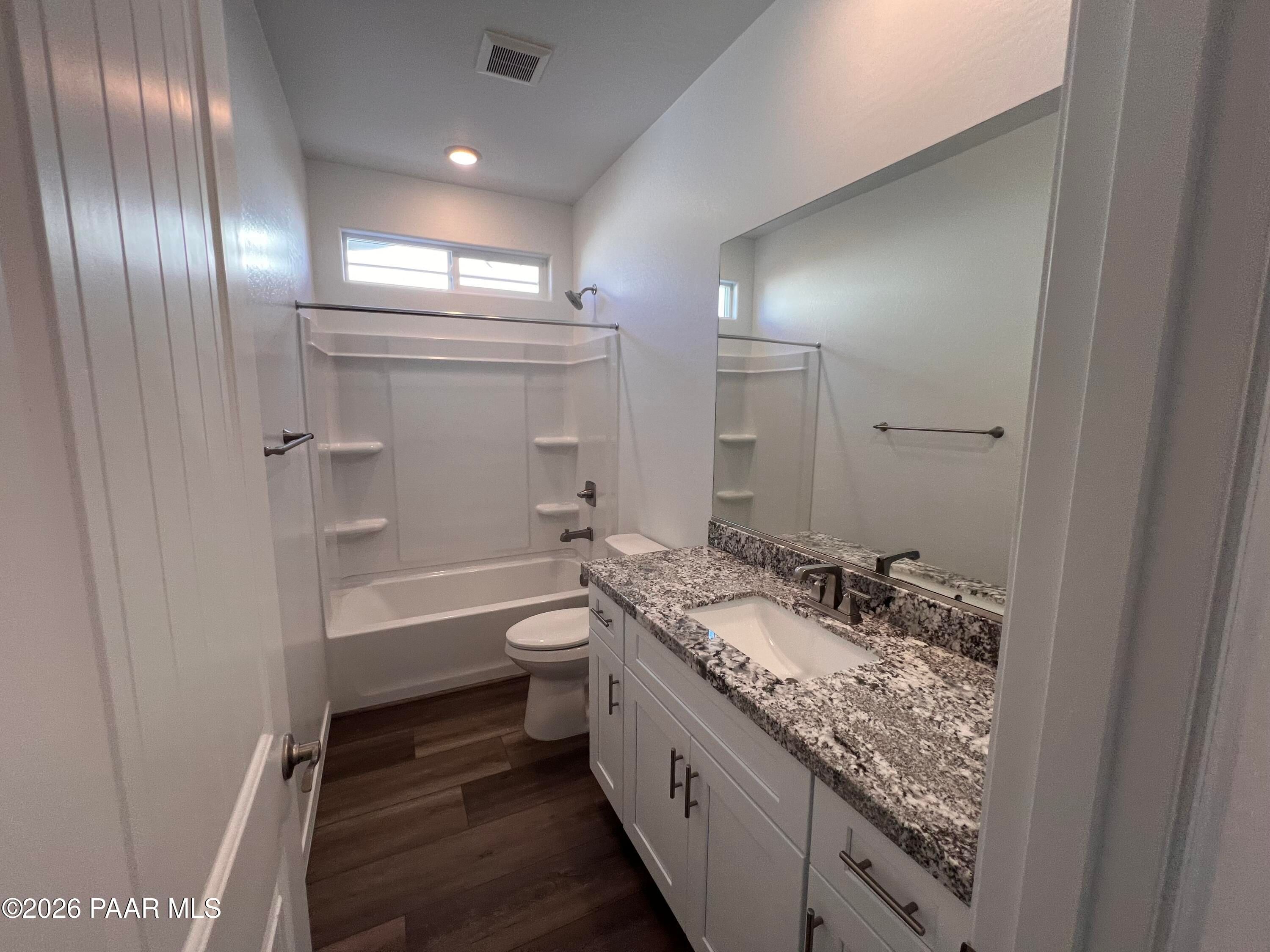 Modern bathroom featuring granite vanity, tub-shower combo, and wood flooring in Davidson Homes The Sunrise II A, Prescott, Arizona