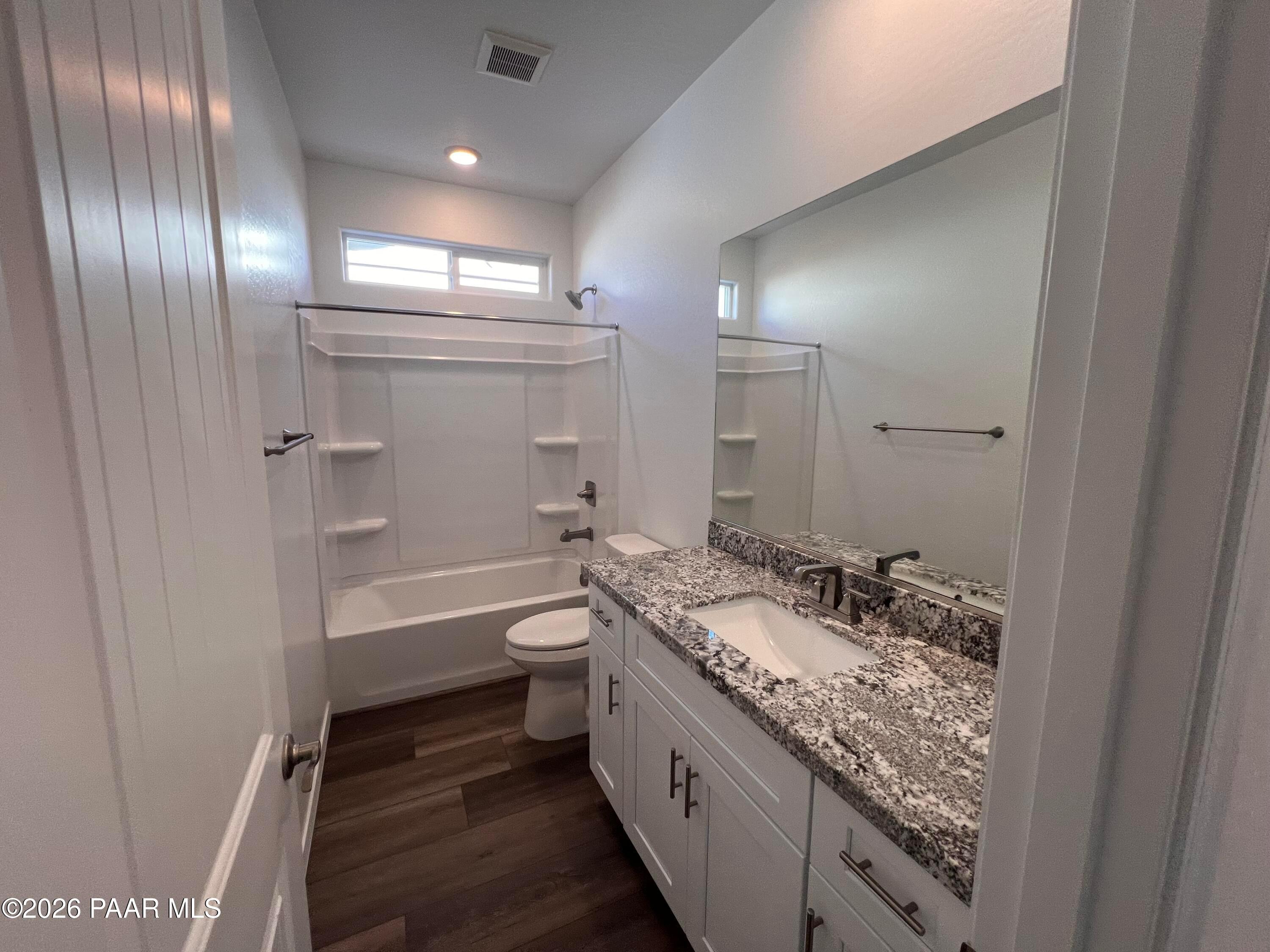 Modern bathroom featuring granite vanity, tub-shower combo, and wood flooring in Davidson Homes The Sunrise II A, Prescott, Arizona