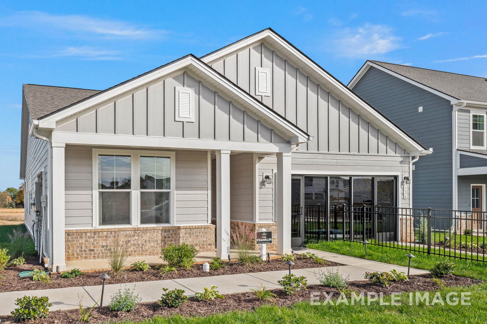 Exterior of The Franklin B single-story home by Davidson Homes: gray board-and-batten siding, brick accents, covered porch, 2-car garage
