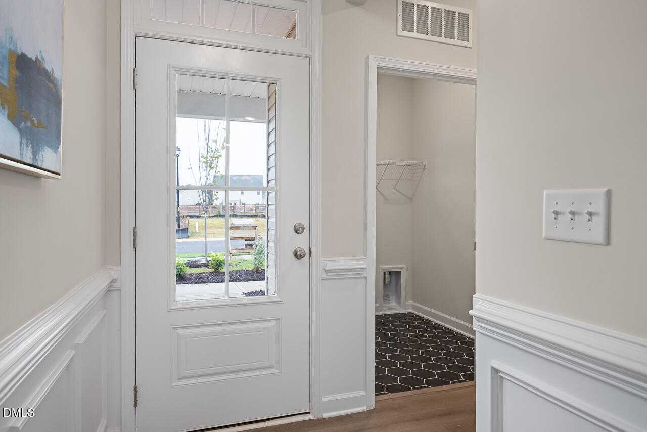 Bright entry foyer with glass-paneled white door overlooking porch, coat closet and pet door in Davidson Homes The Carter C, Lillington NC