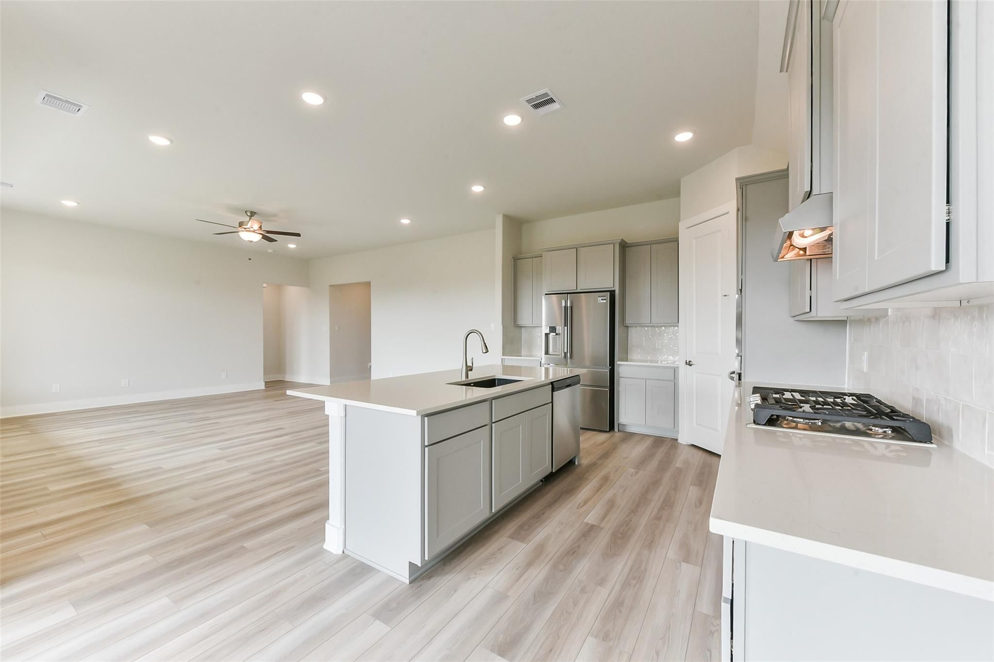 Modern open-concept kitchen with white shaker cabinets, quartz island, stainless appliances in Davidson Homes The Edward A, Lago Mar