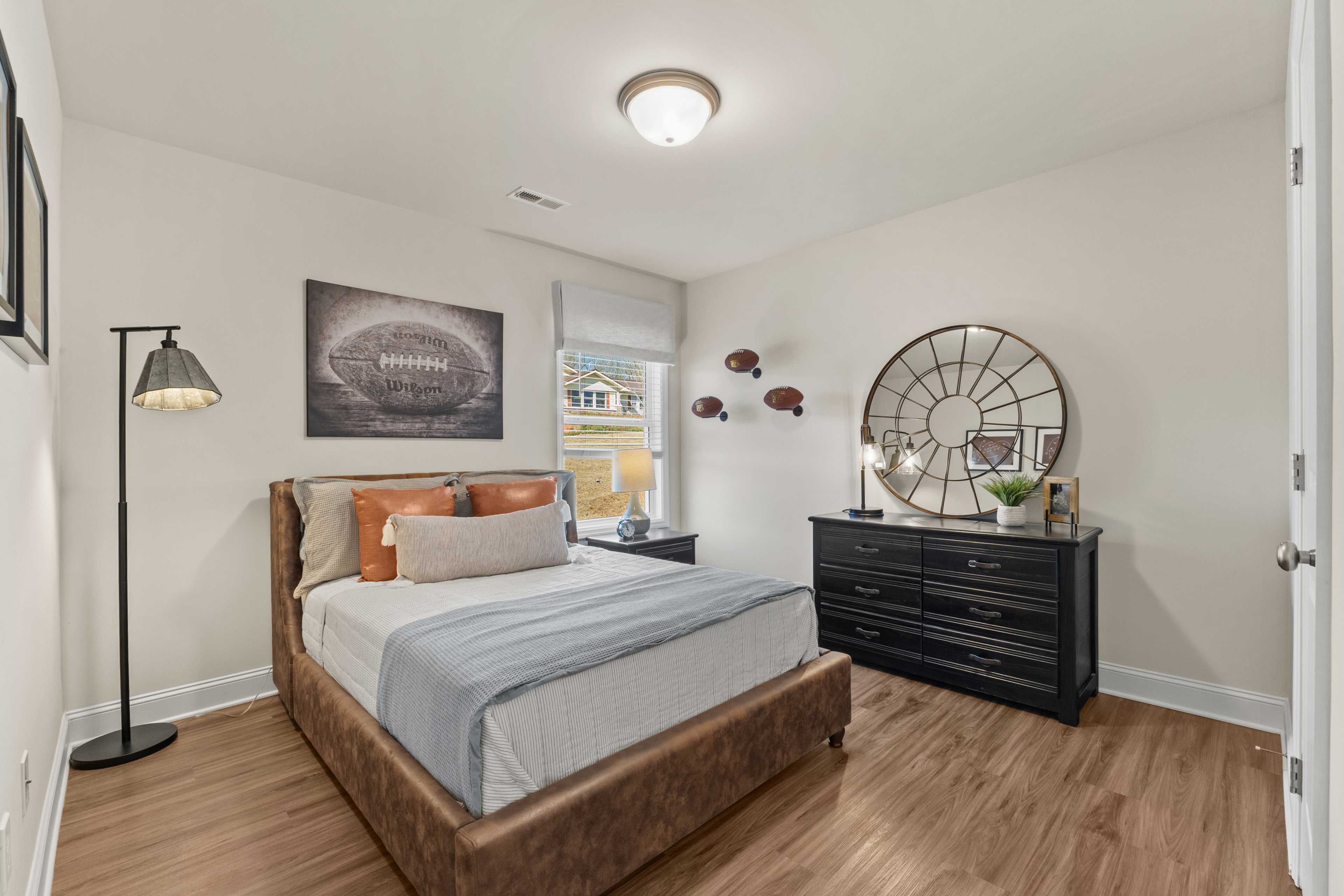 Sports-themed bedroom at Ramsay Cove in Owens Cross Roads Alabama with queen bed, hardwood floors, football art, and arched mirror