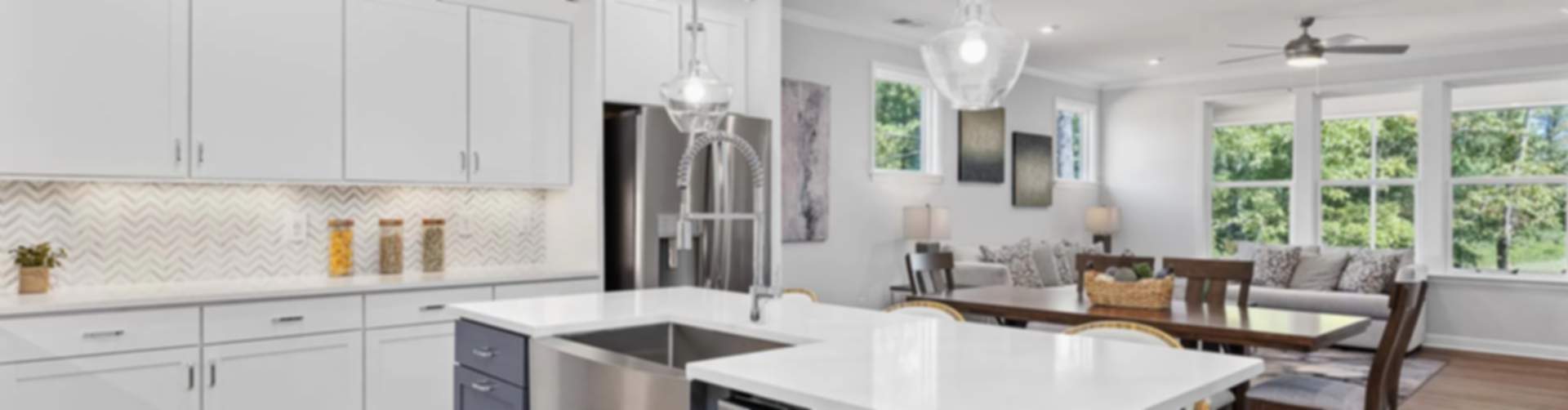 Spacious open-concept kitchen in Belmont new home with white cabinets, navy island, pendant lights, and hardwood floors