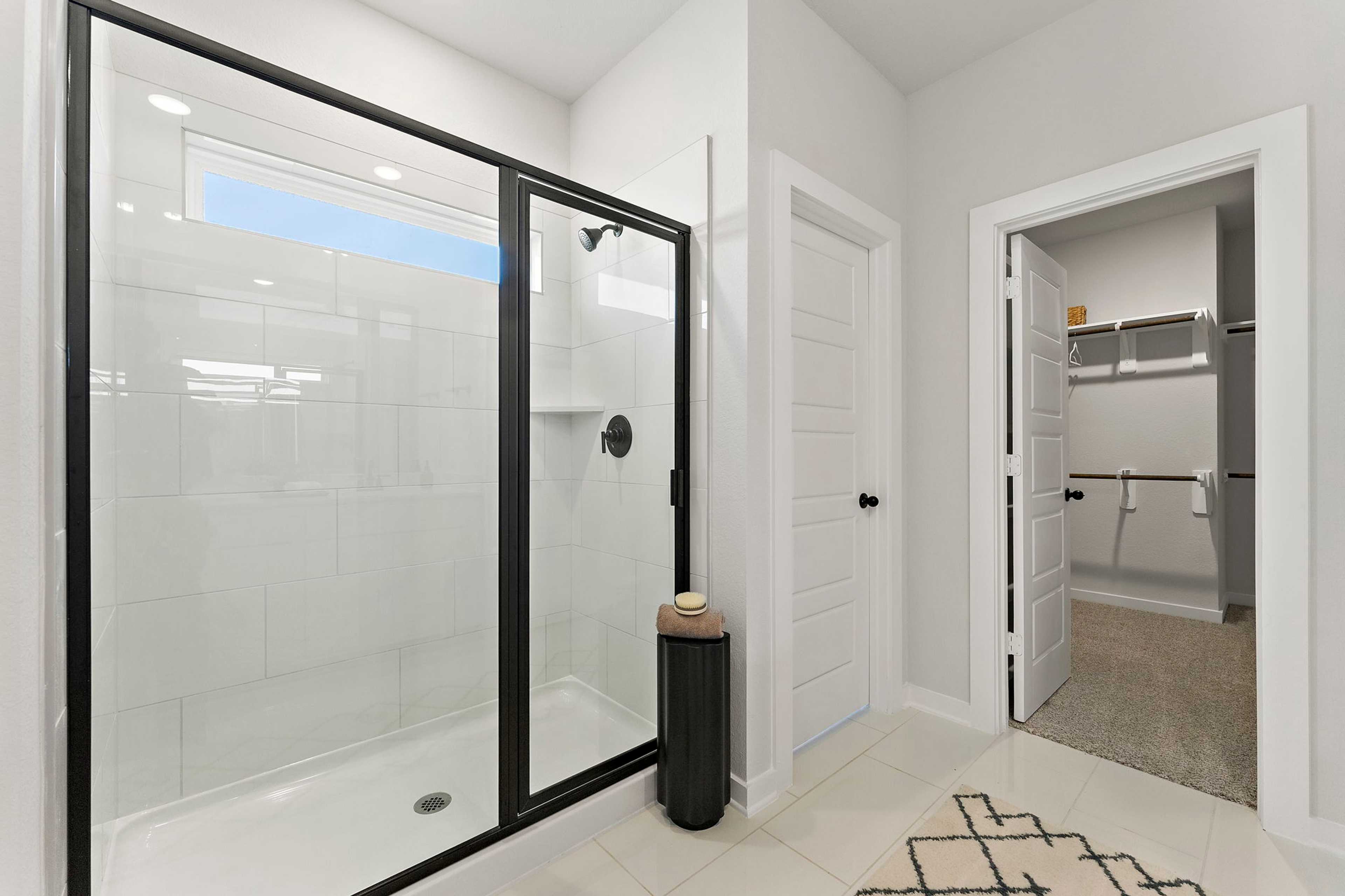 Modern primary bathroom at Sundance Cove in Crosby, Texas with frameless glass shower and walk-in closet