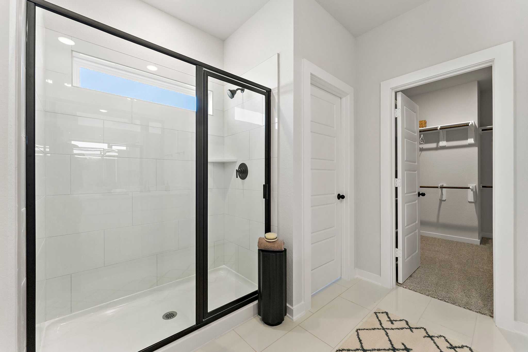 Spacious primary bathroom at Sundance Cove in Crosby TX with frameless glass walk-in shower, white subway tiles and adjacent closet