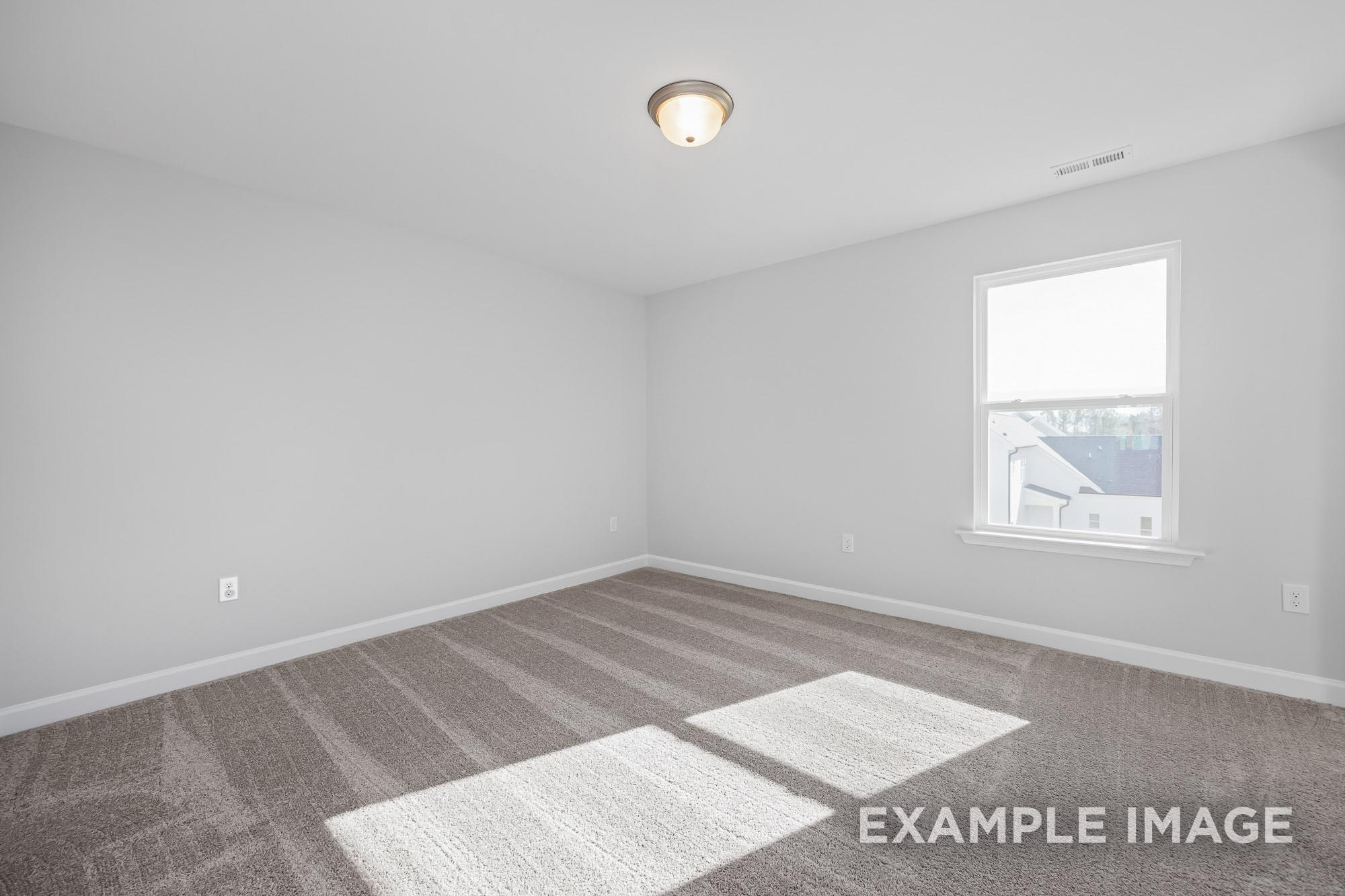 Bright secondary bedroom in The Cypress C II featuring light gray walls, beige carpet flooring, and large sunny window