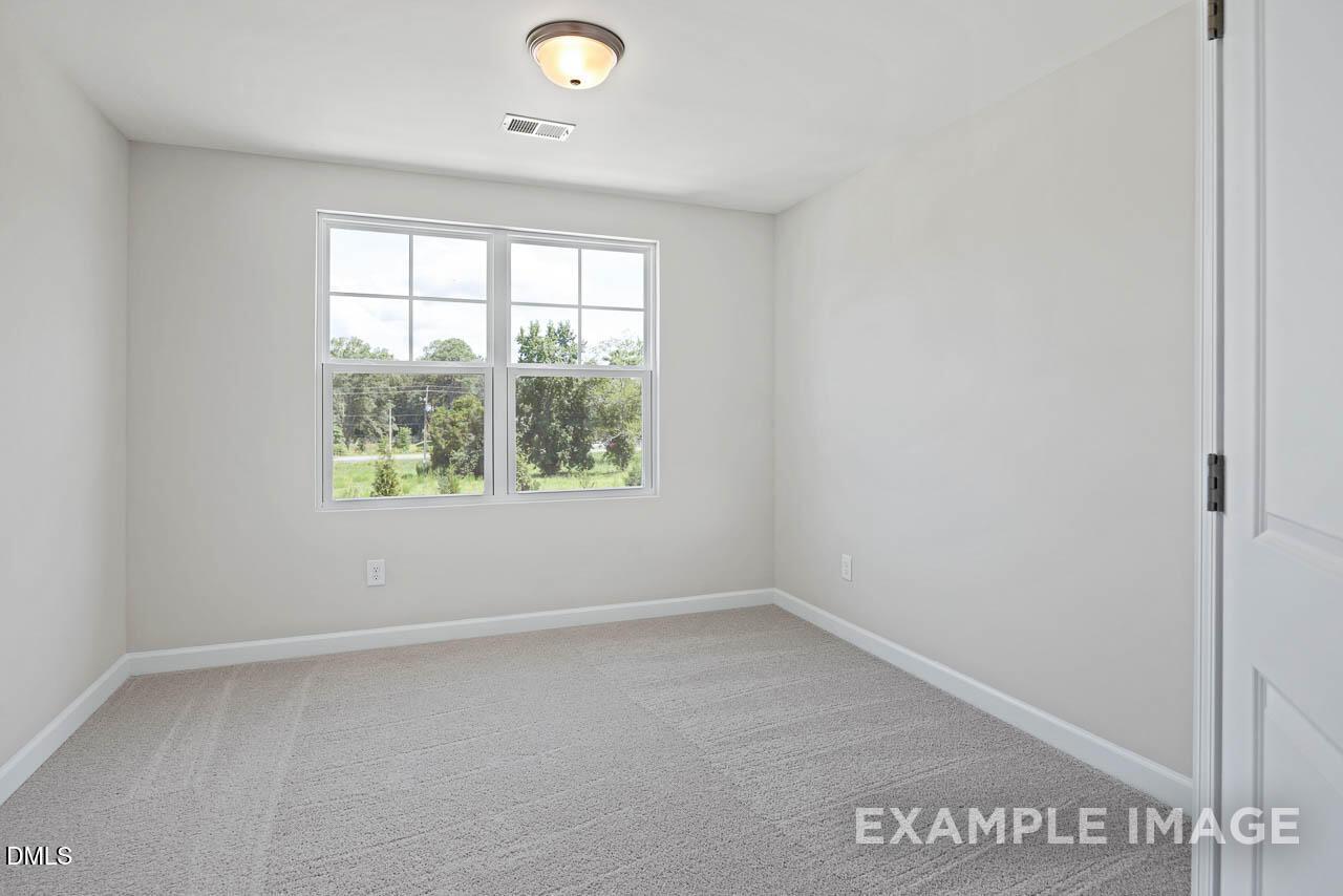 Bright, carpeted bedroom with large window in The Graham floor plan by Davidson Homes in Springvale, Fuquay-Varina, NC.