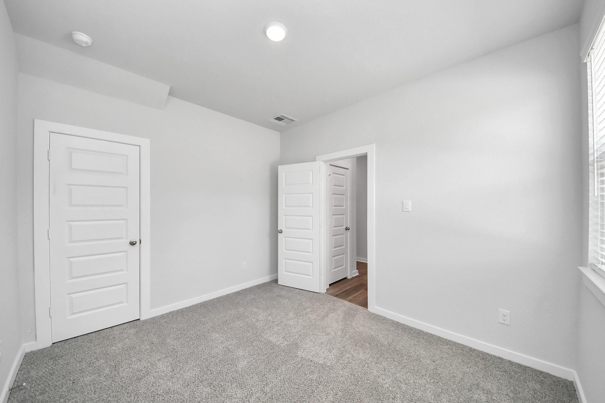 Bright, carpeted secondary bedroom in The Sabine E floor plan at Liberty Estates, Cleveland, Texas.