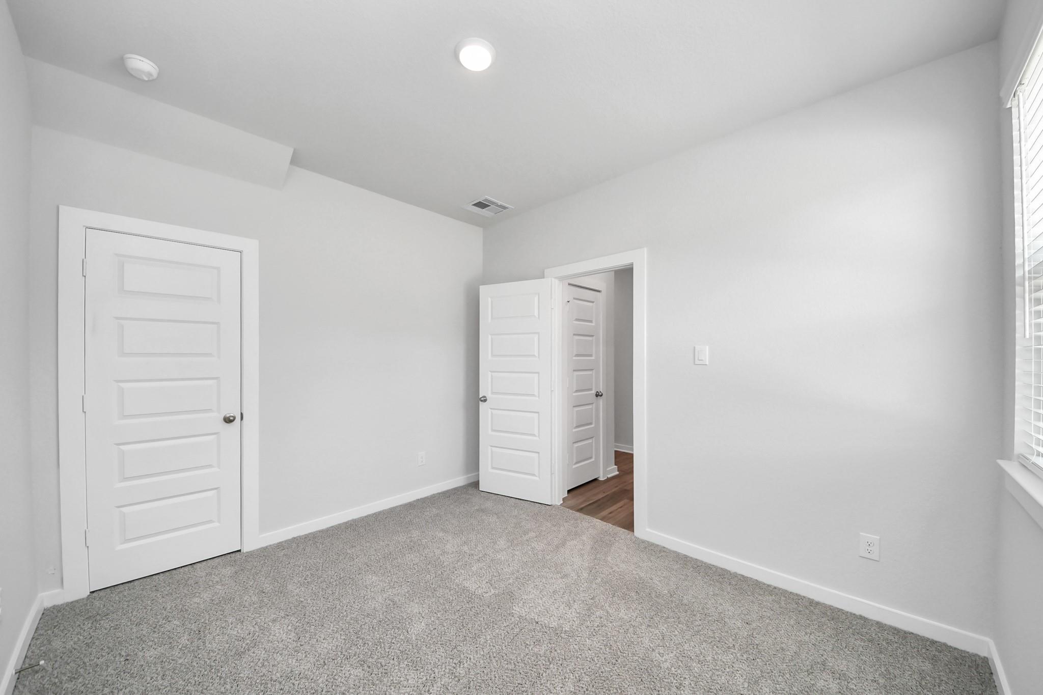 Bright, carpeted secondary bedroom in The Sabine E floor plan at Liberty Estates, Cleveland, Texas.