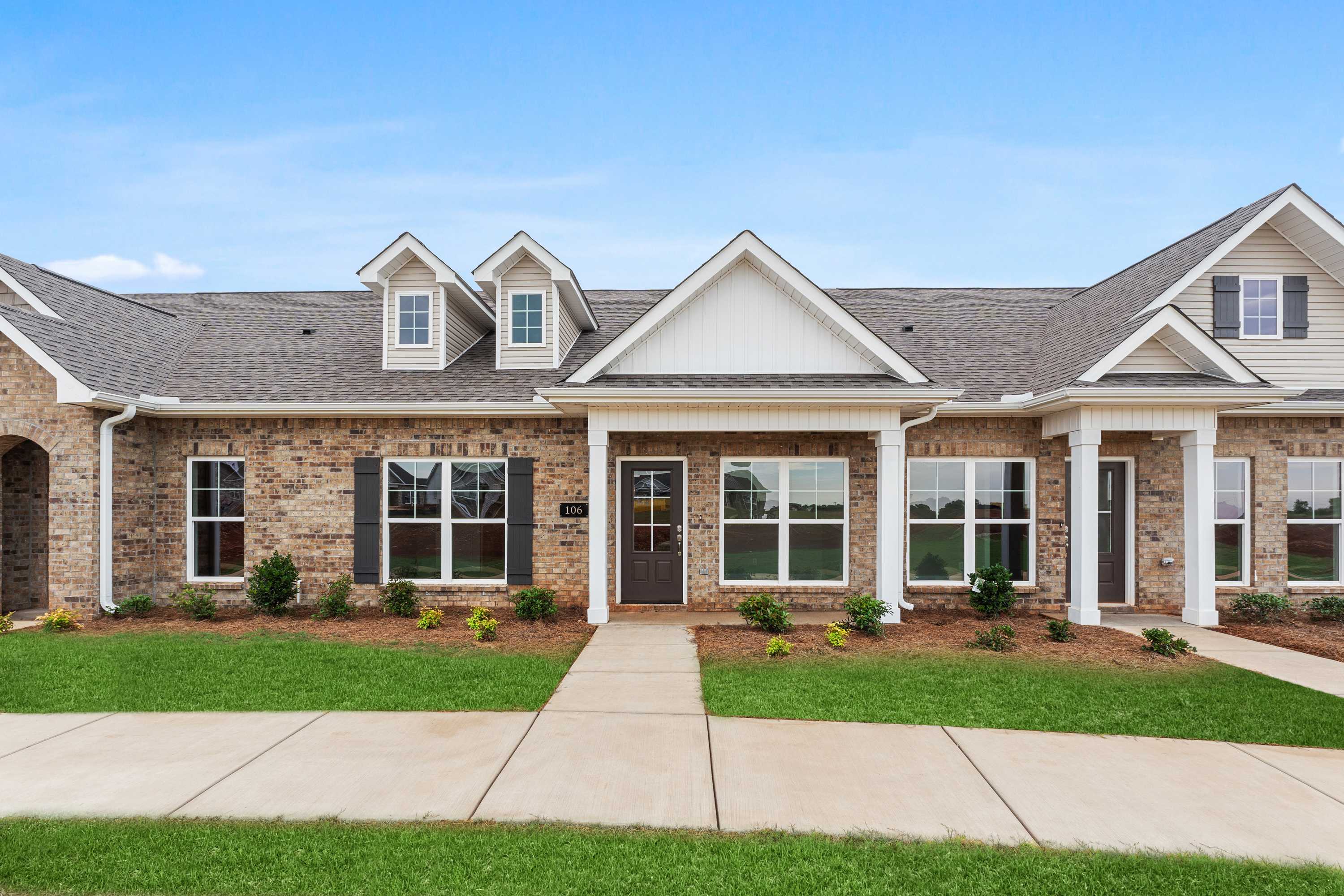 Charming one-story Copeland B multi-family home exterior featuring brick and white siding, covered porch, garage, and manicured lawn in Madison, Alabama