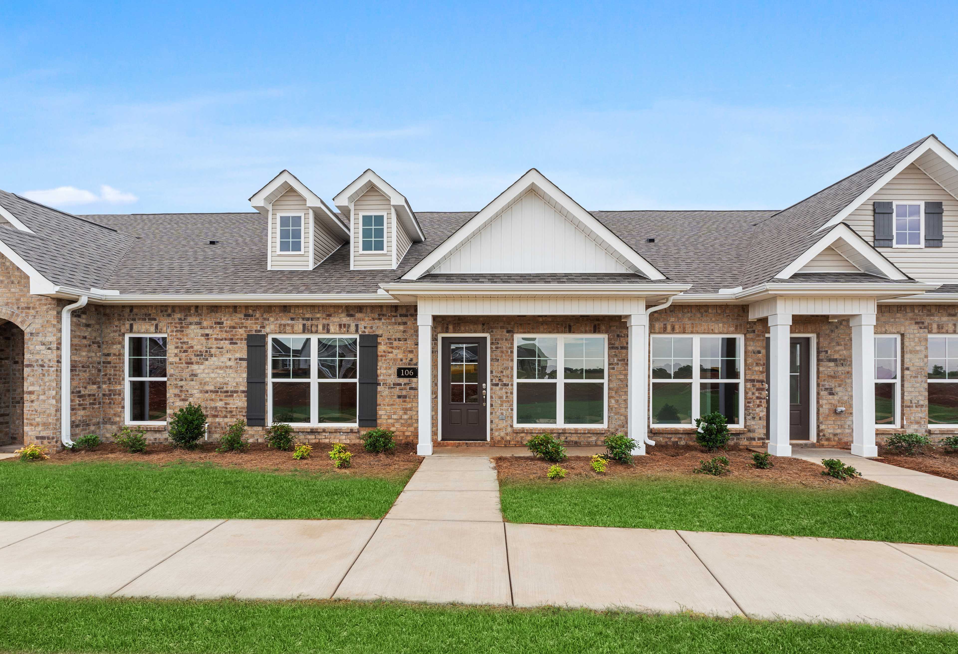 Charming one-story Copeland B multi-family home exterior featuring brick and white siding, covered porch, garage, and manicured lawn in Madison, Alabama