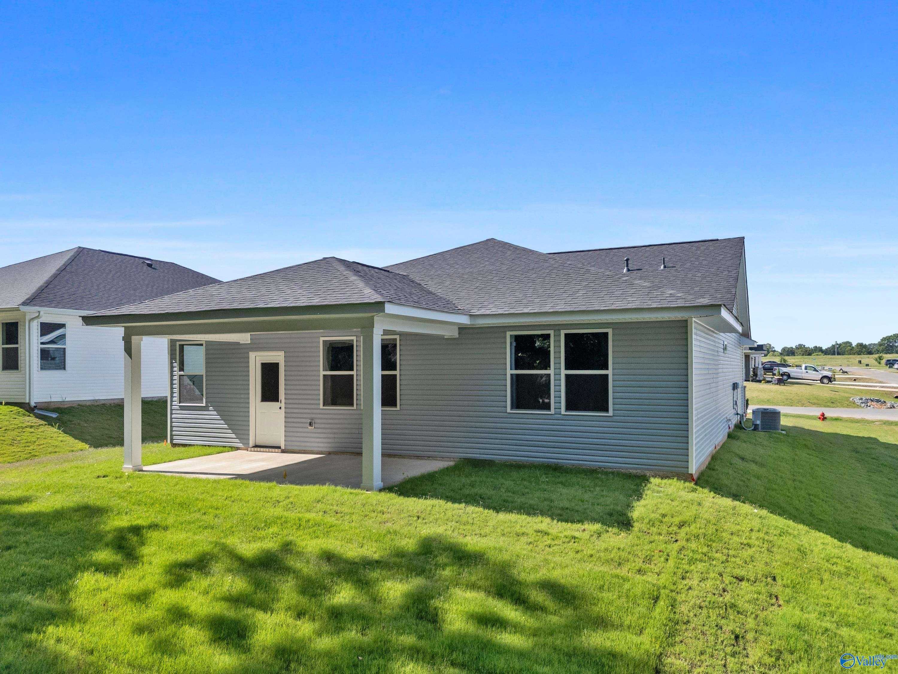 Rear view of The Phoenix single-story home with covered patio, gray siding, and lush green yard in Bailey Park, Fayetteville, Tennessee