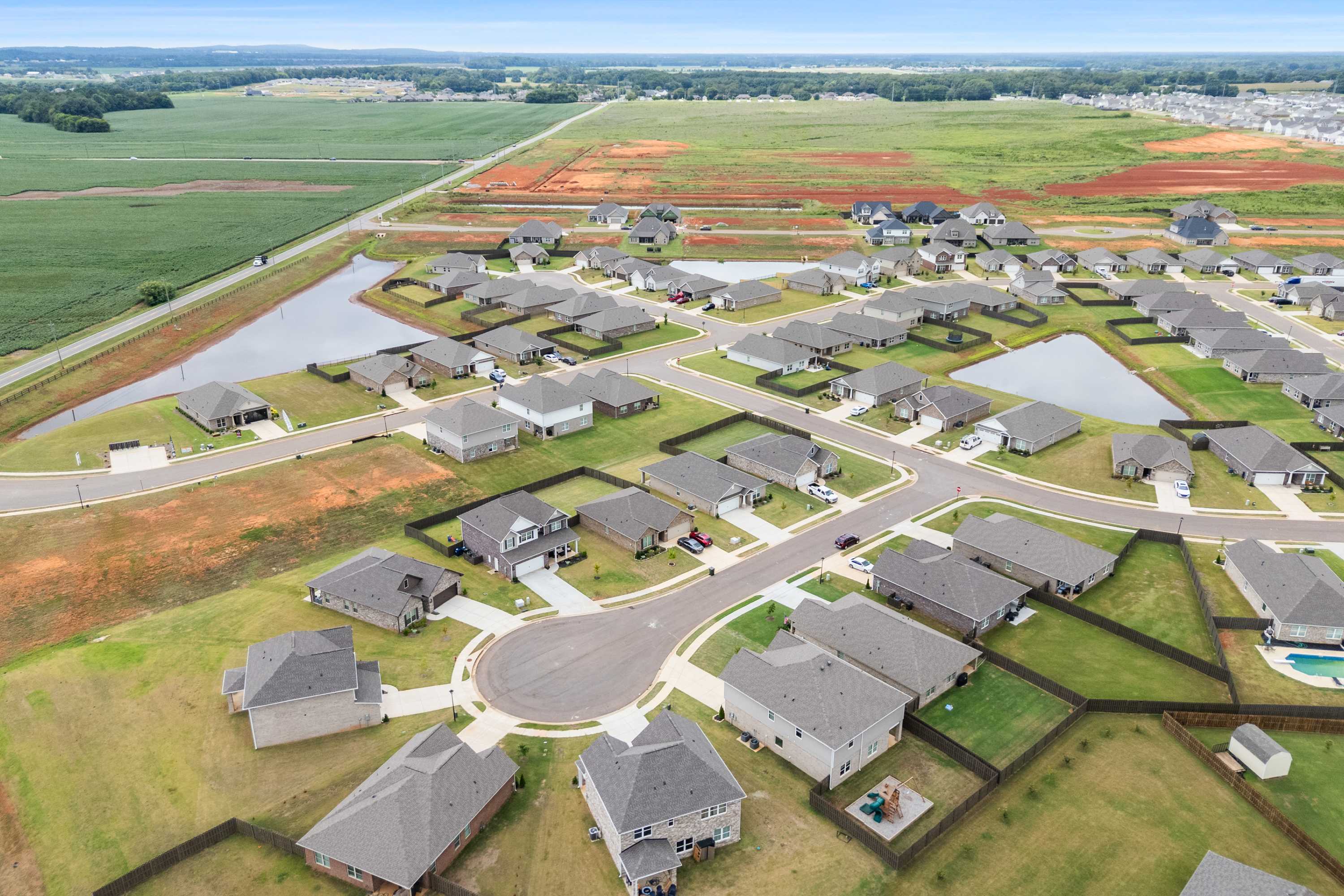 Aerial view of Heritage Lakes neighborhood in New Market, Alabama by Davidson Homes featuring homes, ponds, and green fields