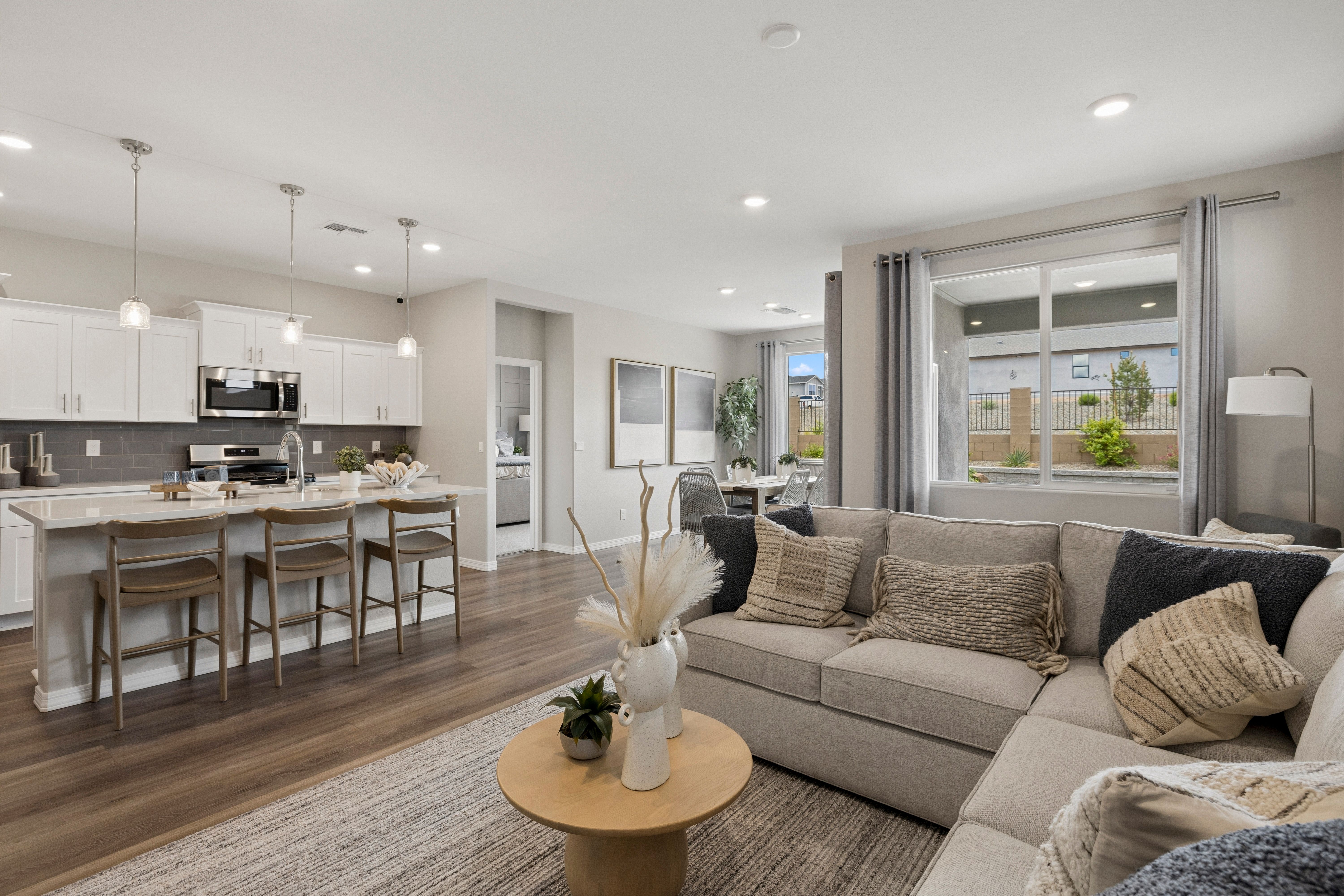 Open-concept kitchen and living room in South Ranch Prescott AZ home with white island, hardwood floors, and neutral sofa seating