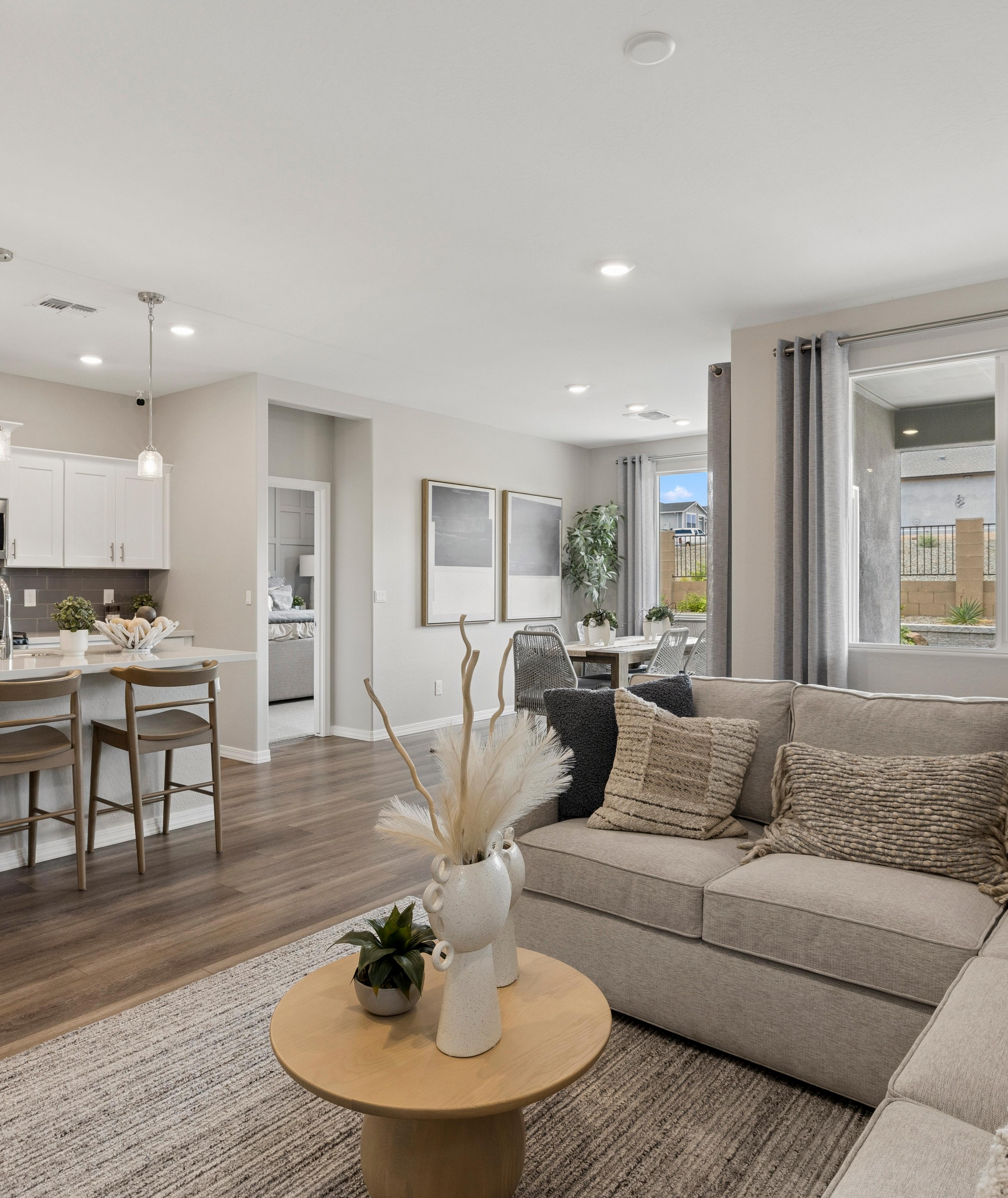 Open-concept kitchen and living room in South Ranch Prescott AZ home with white island, hardwood floors, and neutral sofa seating