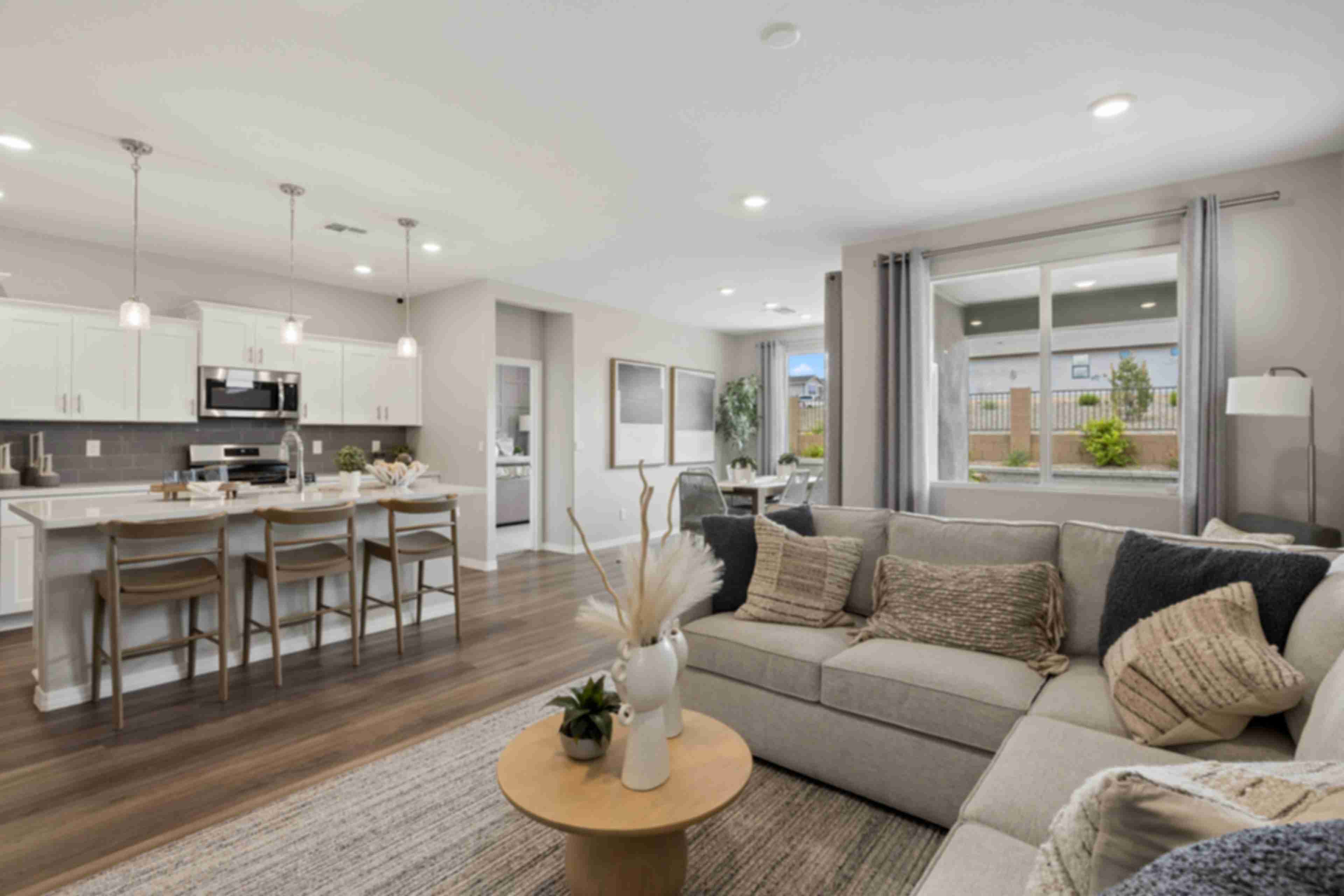 Open-concept kitchen and living room in South Ranch Prescott AZ home with white island, hardwood floors, and neutral sofa seating