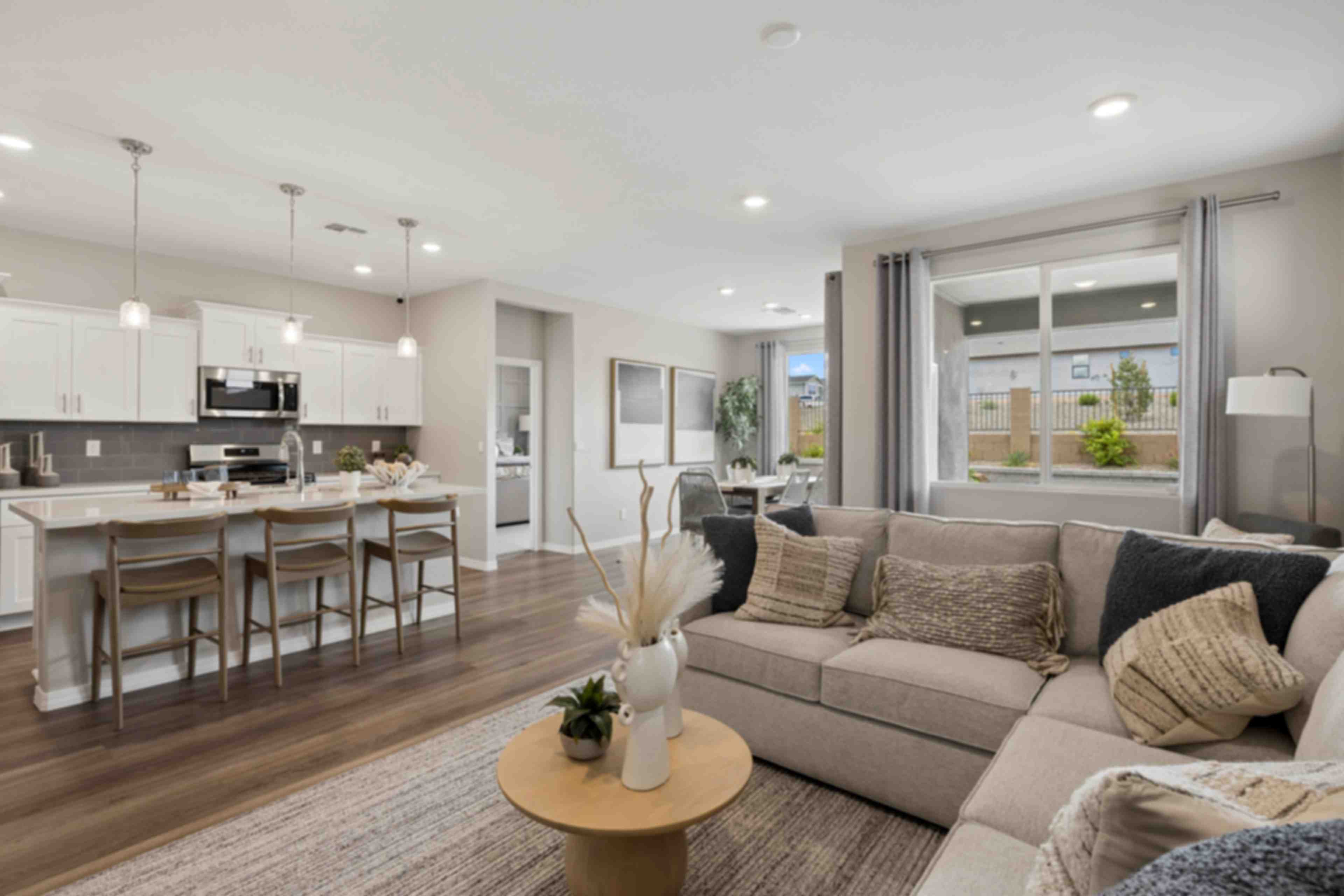 Open-concept kitchen and living room in South Ranch Prescott AZ home with white island, hardwood floors, and neutral sofa seating