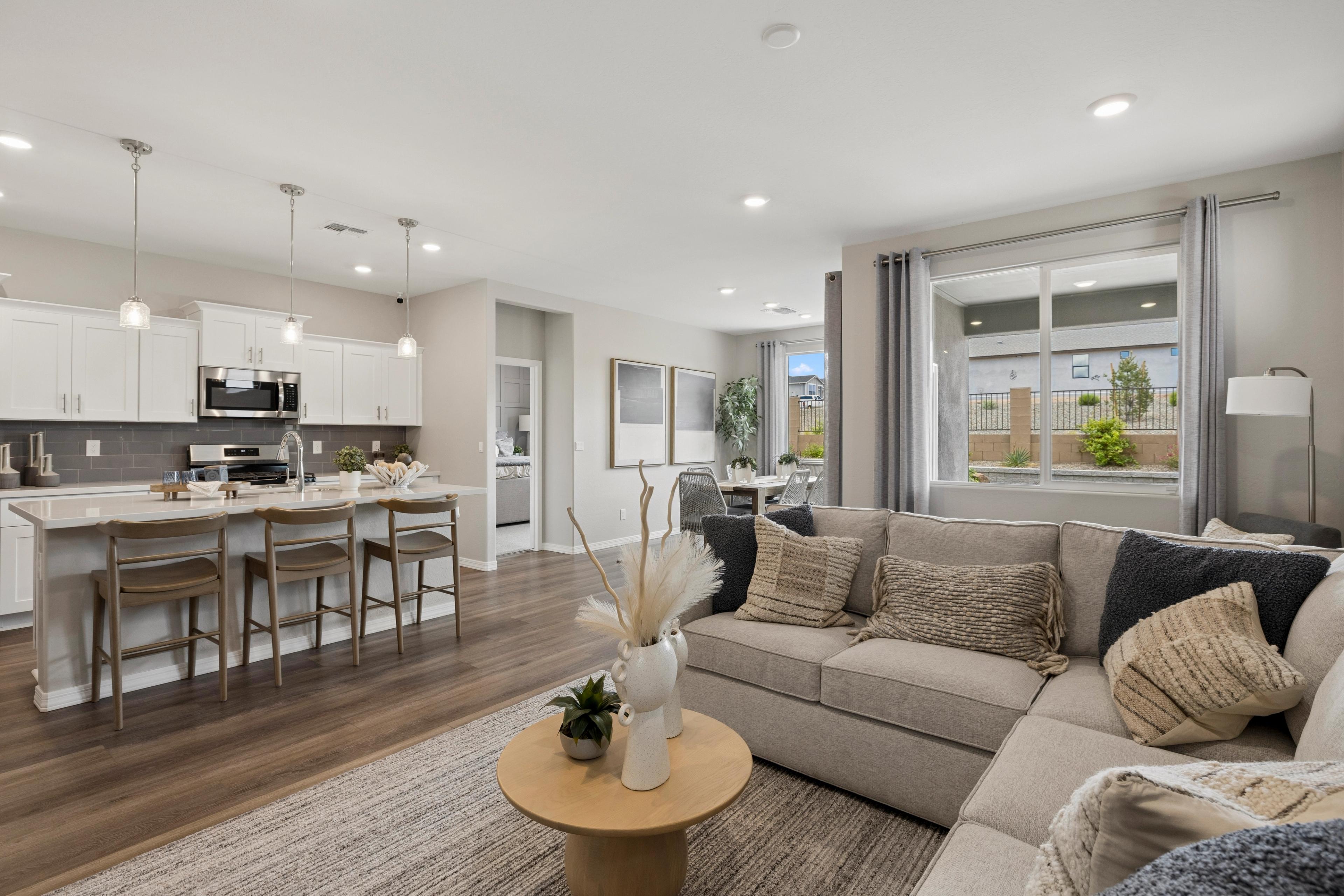 Open-concept kitchen and living room in South Ranch Prescott AZ home with white island, hardwood floors, and neutral sofa seating