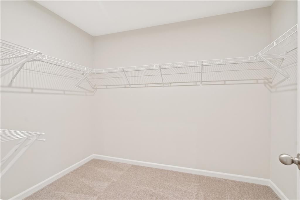 Spacious walk-in closet with white wire shelving and beige walls in The Cary B master suite by Davidson Homes, Kennesaw, GA