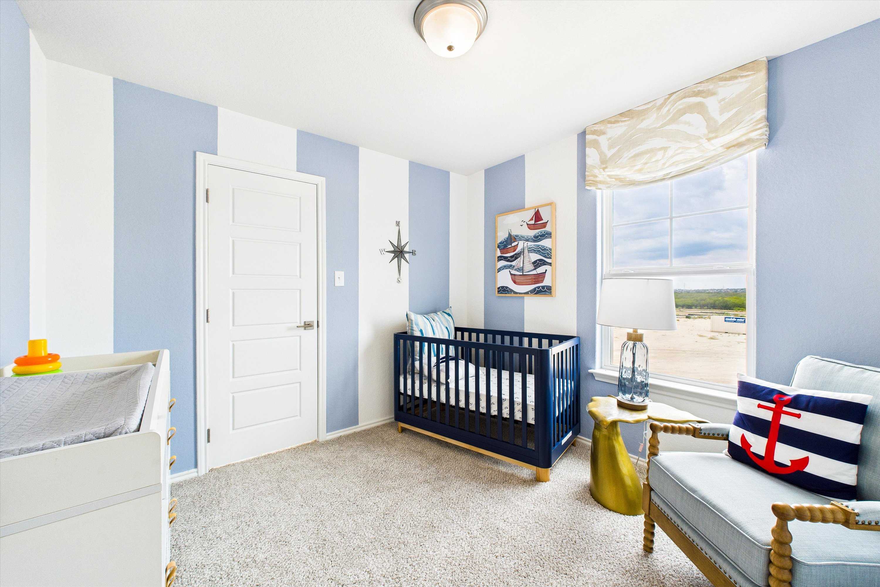 Nautical nursery in Fairway Crossing Converse TX with blue striped walls navy crib rocking chair and anchor decor