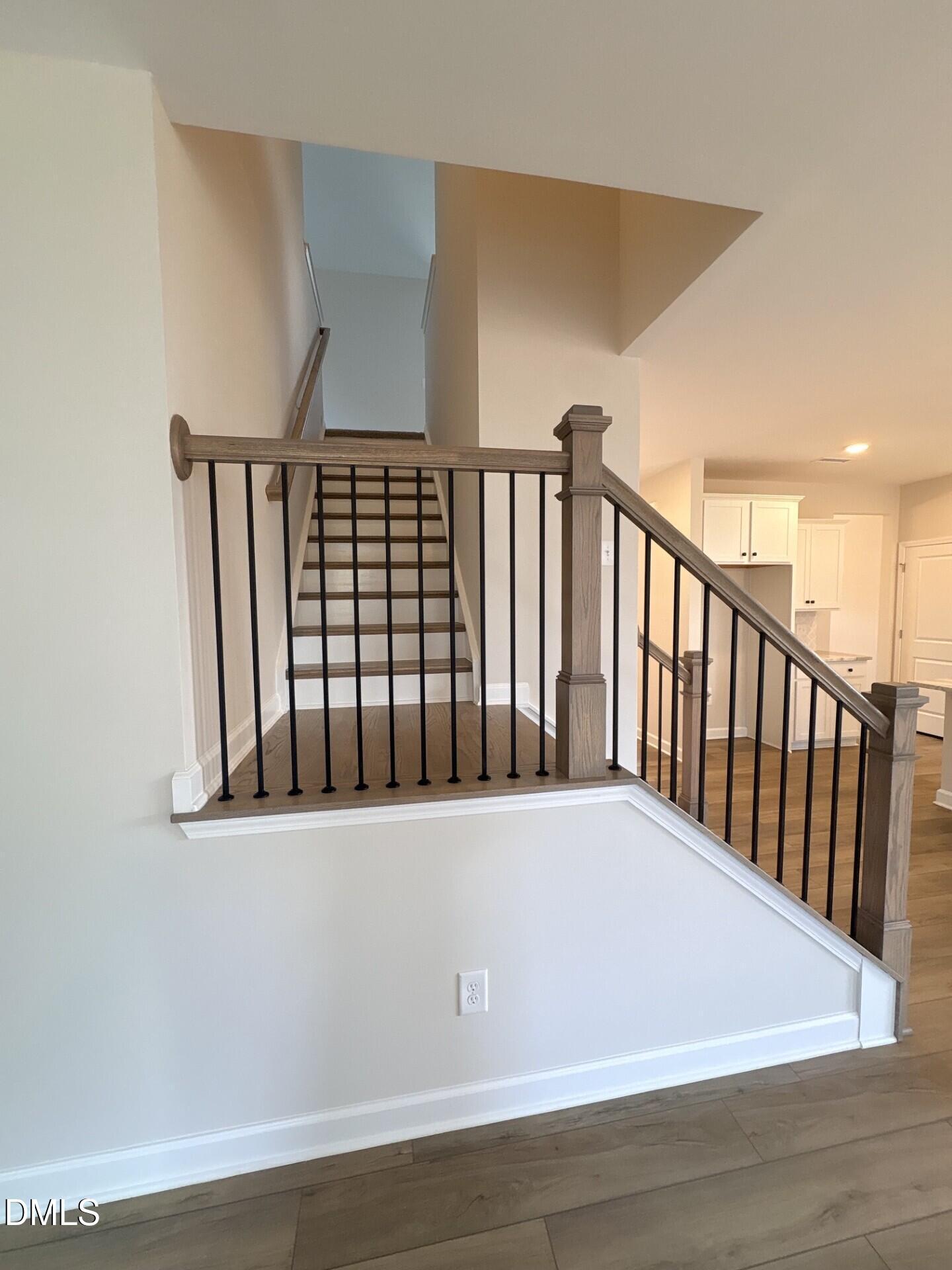 Modern staircase with wood handrail and black iron balusters in The Ash C floor plan at Woodland Crossing, Zebulon, NC.