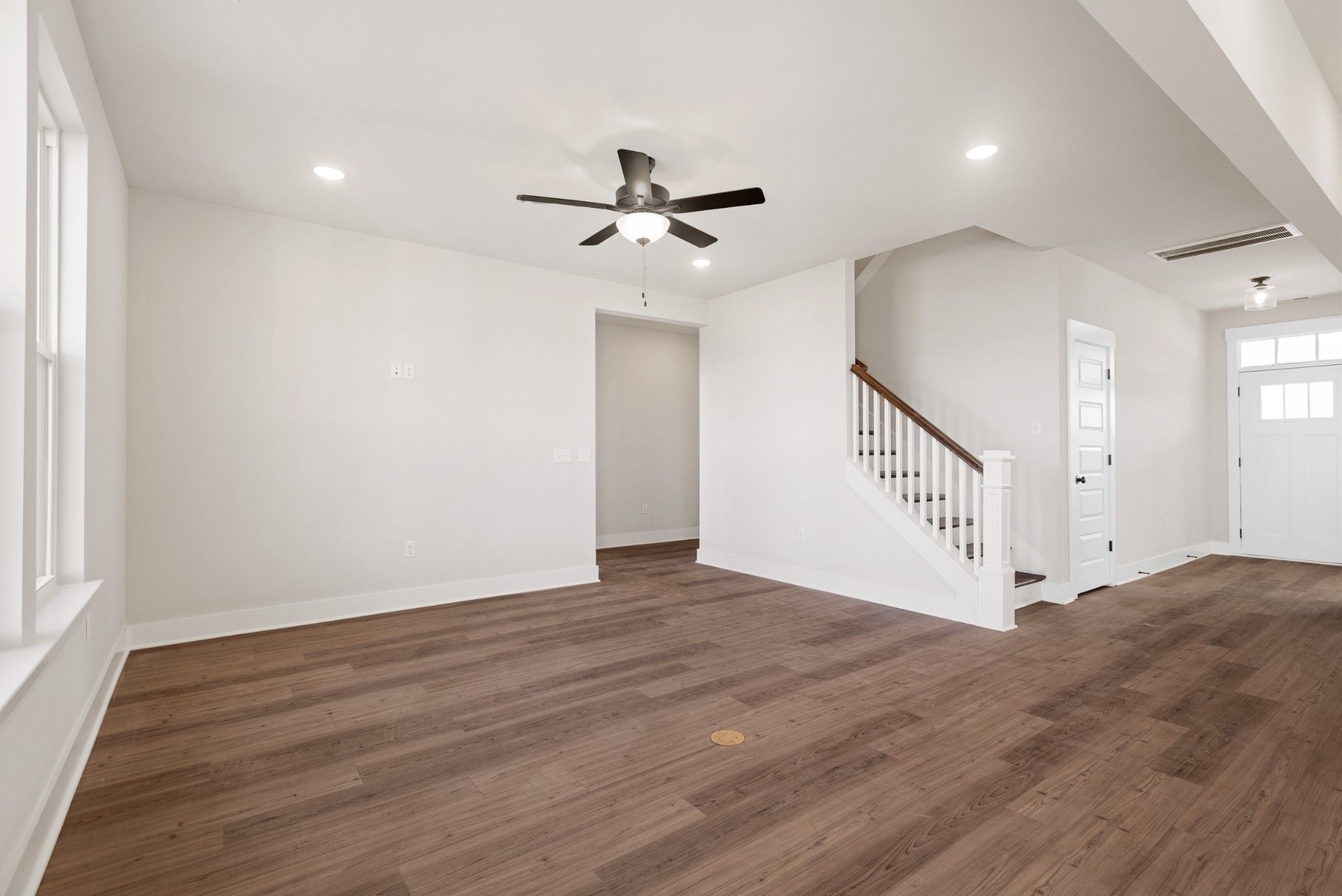 Bright, open-concept living area with wood floors and staircase in The Willow B floor plan, Calista Farms, White House, TN.