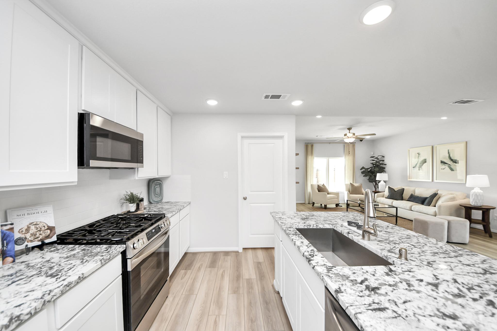 Modern kitchen with granite island and white cabinets at Sunterra in Katy, Texas by Davidson Homes.