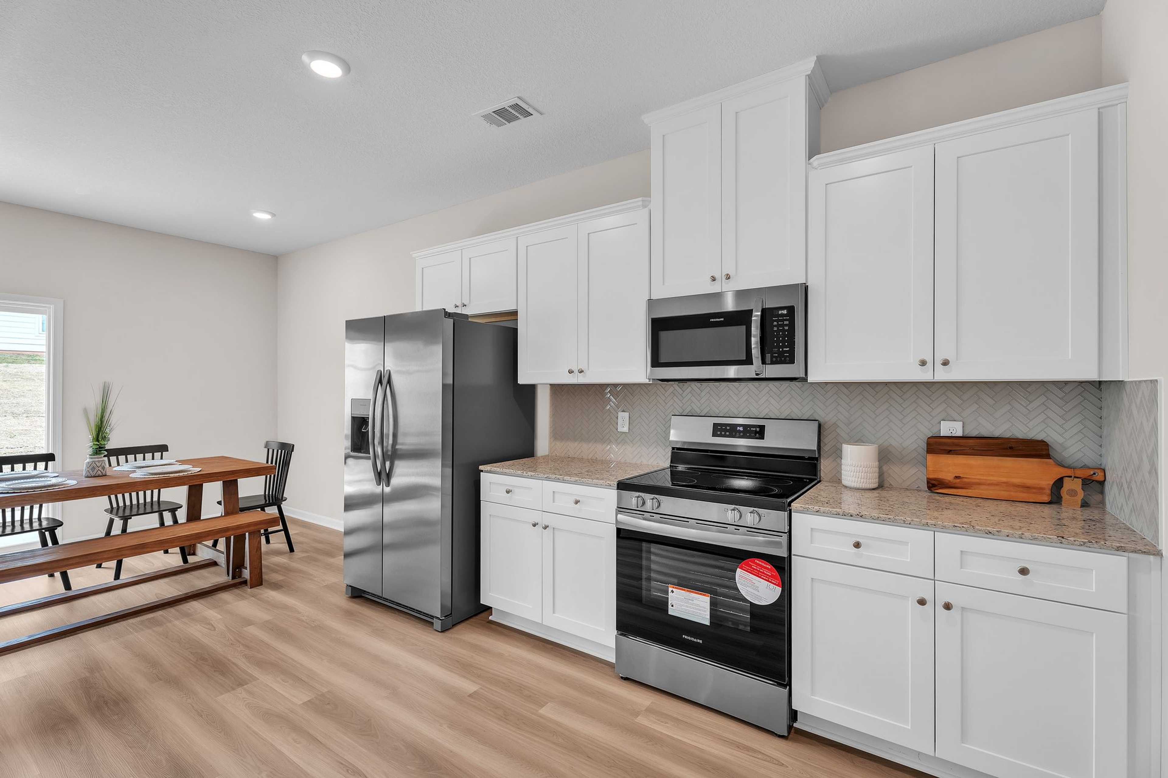 Spacious kitchen in Summer Vineyard Phenix City AL home with white shaker cabinets, stainless steel appliances, and hardwood floors