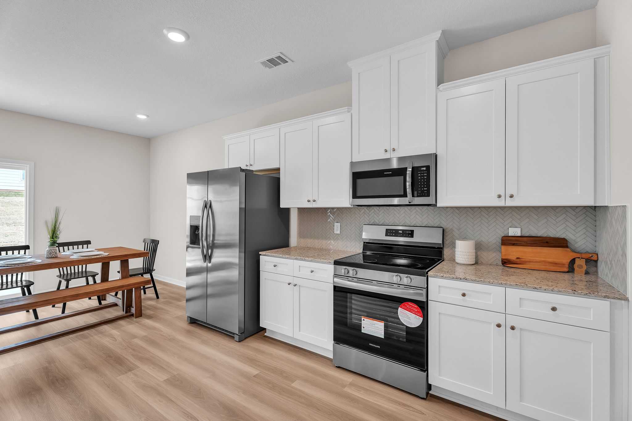 Spacious kitchen in Summer Vineyard Phenix City AL home with white shaker cabinets, stainless steel appliances, and hardwood floors