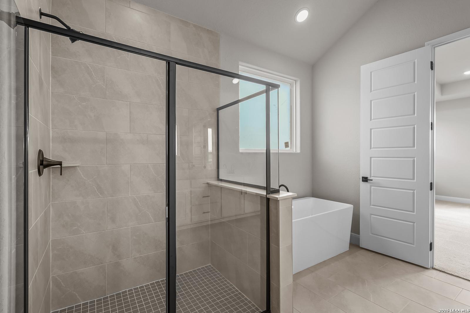 Modern master bathroom with walk-in glass shower and freestanding tub in Davidson Homes The Foster E, Castroville, TX