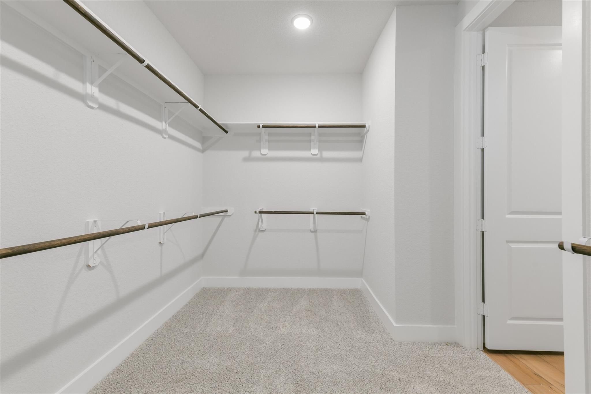 Spacious walk-in closet with wooden shelves and hanging rods in master suite, Davidson Homes The Edward A, Lago Mar, Texas City