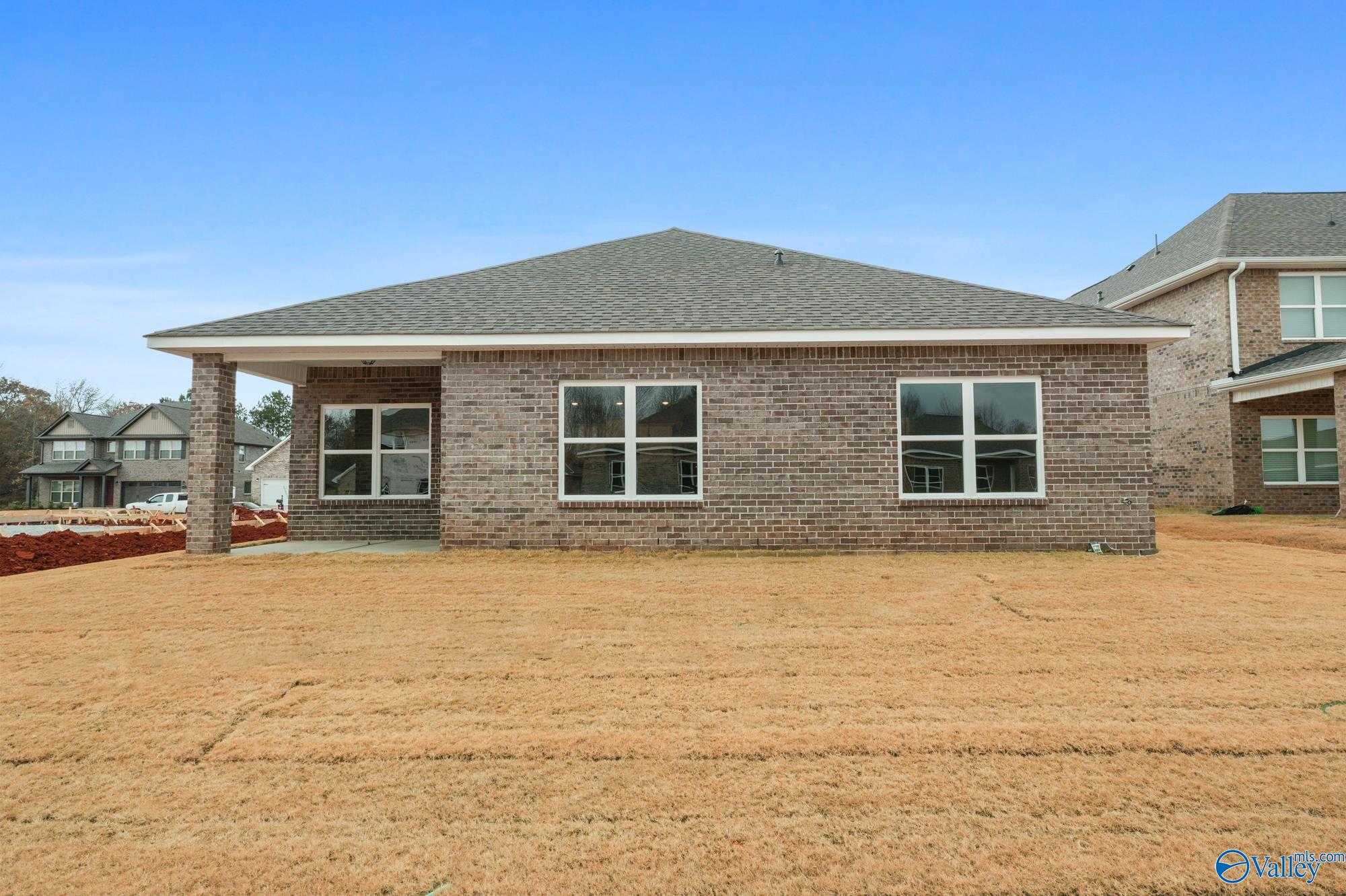 Single-story brick home exterior with gable roof, covered porch, and large windows in Ricketts Farm, Athens, Alabama