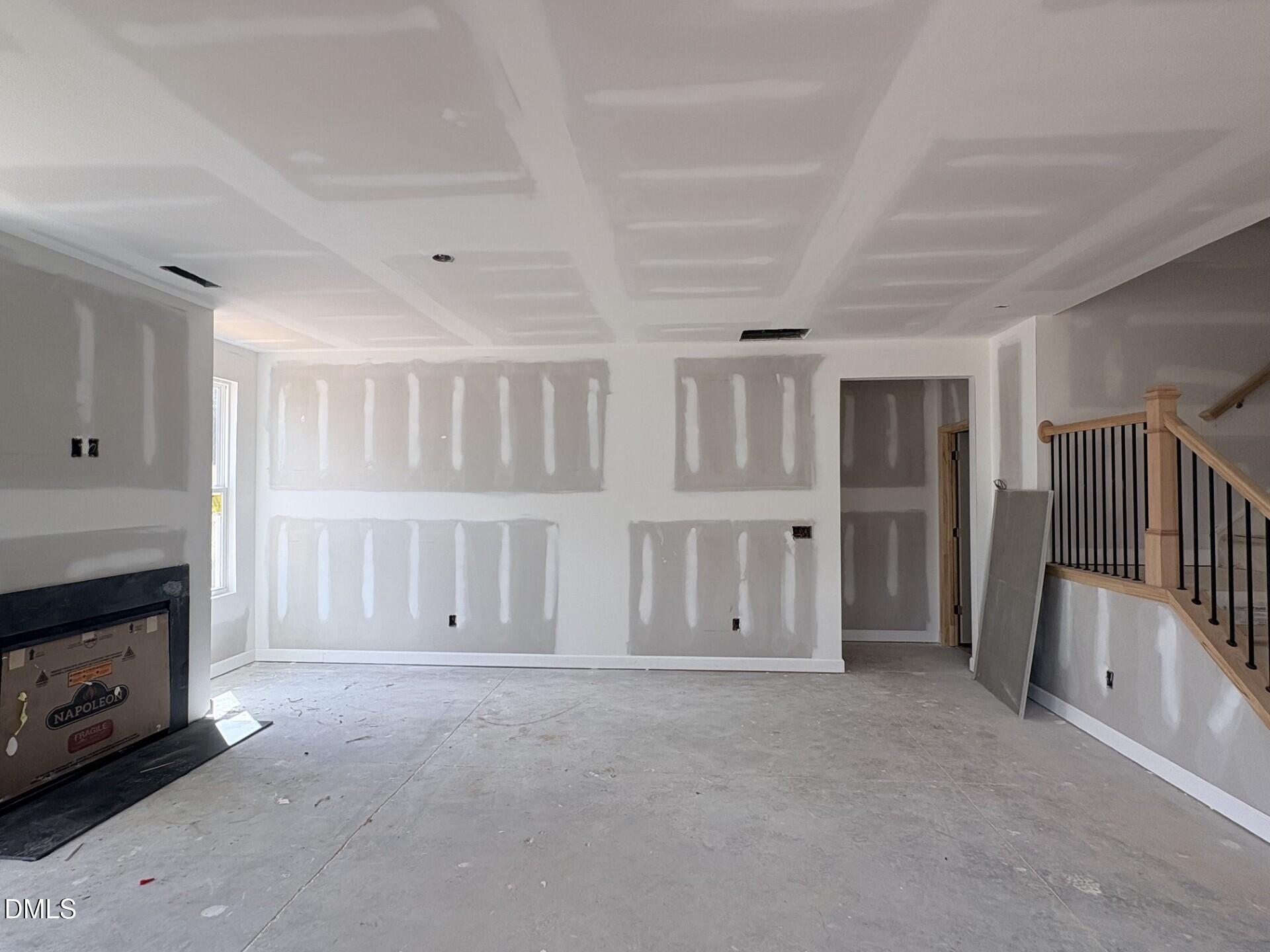 Unfinished living room with fireplace and staircase in The Ash C floor plan at Woodland Crossing, Zebulon, North Carolina.