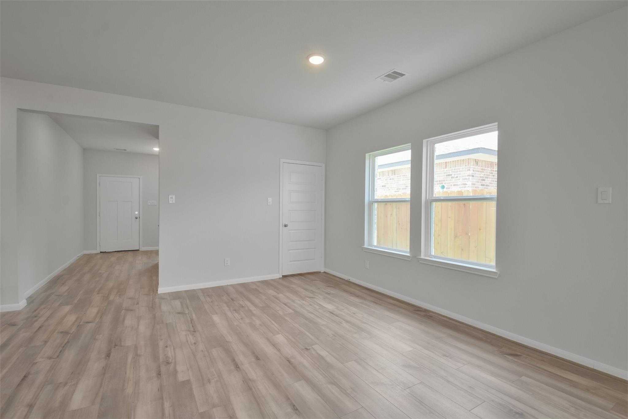 Bright secondary bedroom with large windows overlooking backyard, hardwood floors in Davidson Homes The Tierra A, Dayton, Texas