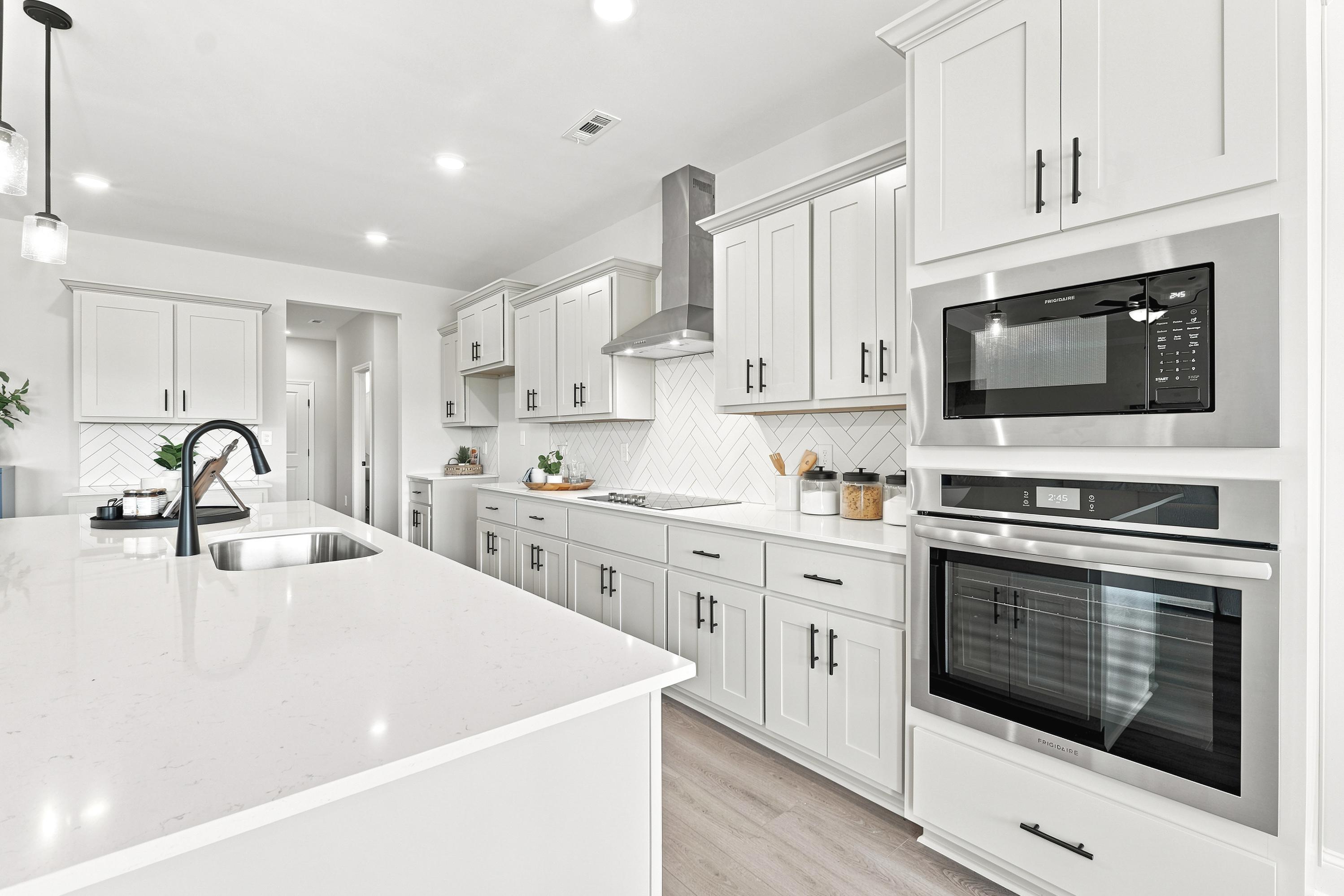 Modern kitchen at Riverton Preserve in Huntsville, AL featuring white cabinetry, quartz countertops, and stainless appliances.