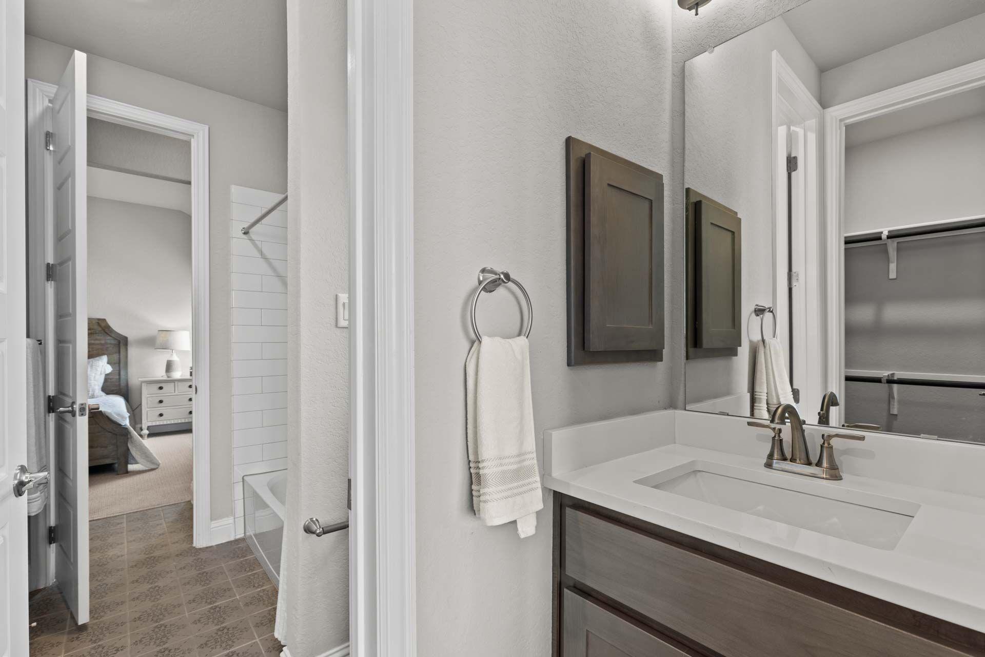 Primary bathroom suite at Ladera in San Antonio TX by Davidson Homes with modern vanity, soaking tub, white towels, and adjacent bedroom view