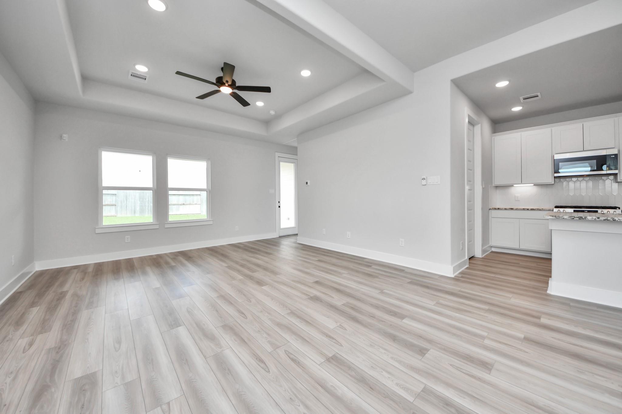 Open-concept living room with tray ceiling and wood-style flooring in Davidson Homes Laguna C floor plan in Sunterra, Katy.