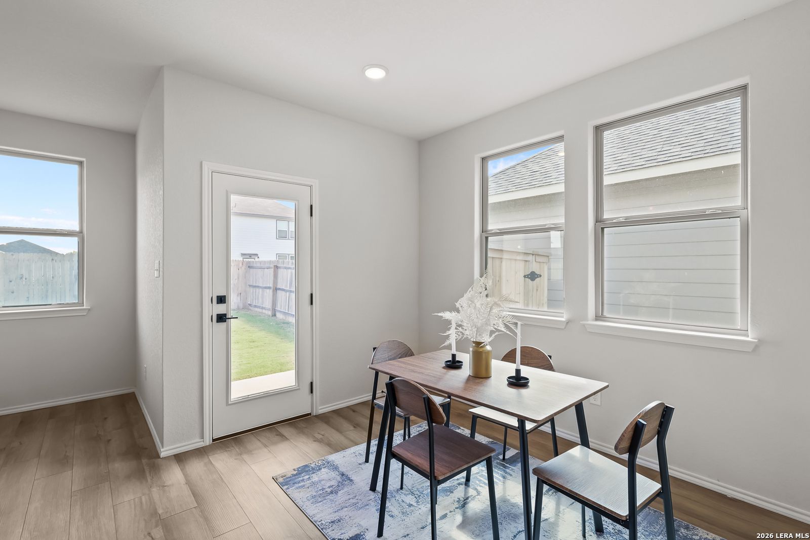 Bright dining room with wooden table, chairs, blue rug, and French doors to lush backyard in The Daphne H, Seguin, Texas