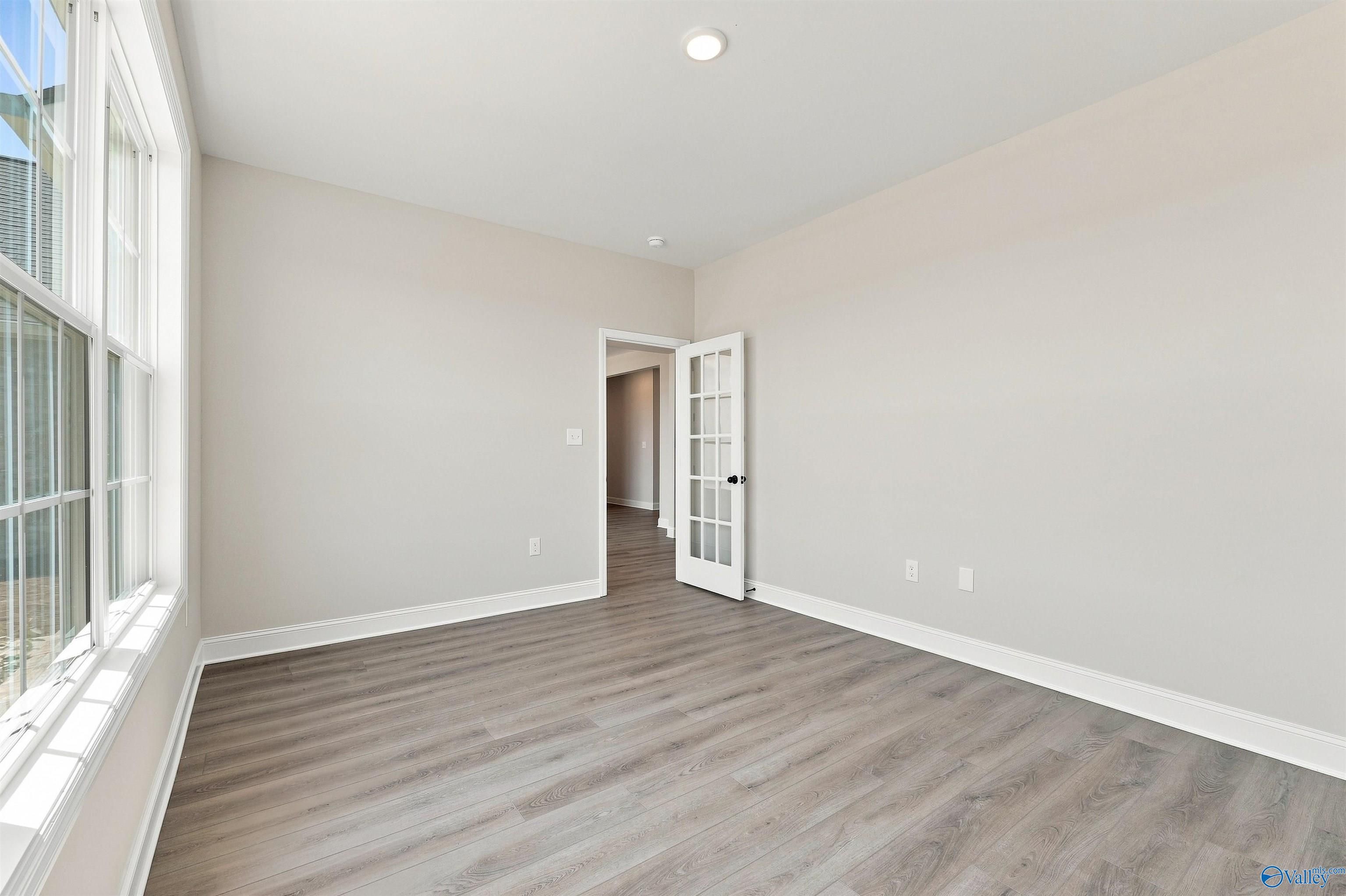 Bright home office or bedroom with French door entry and wood-look flooring in The Oxford plan at Kendall Farms, Toney, AL.