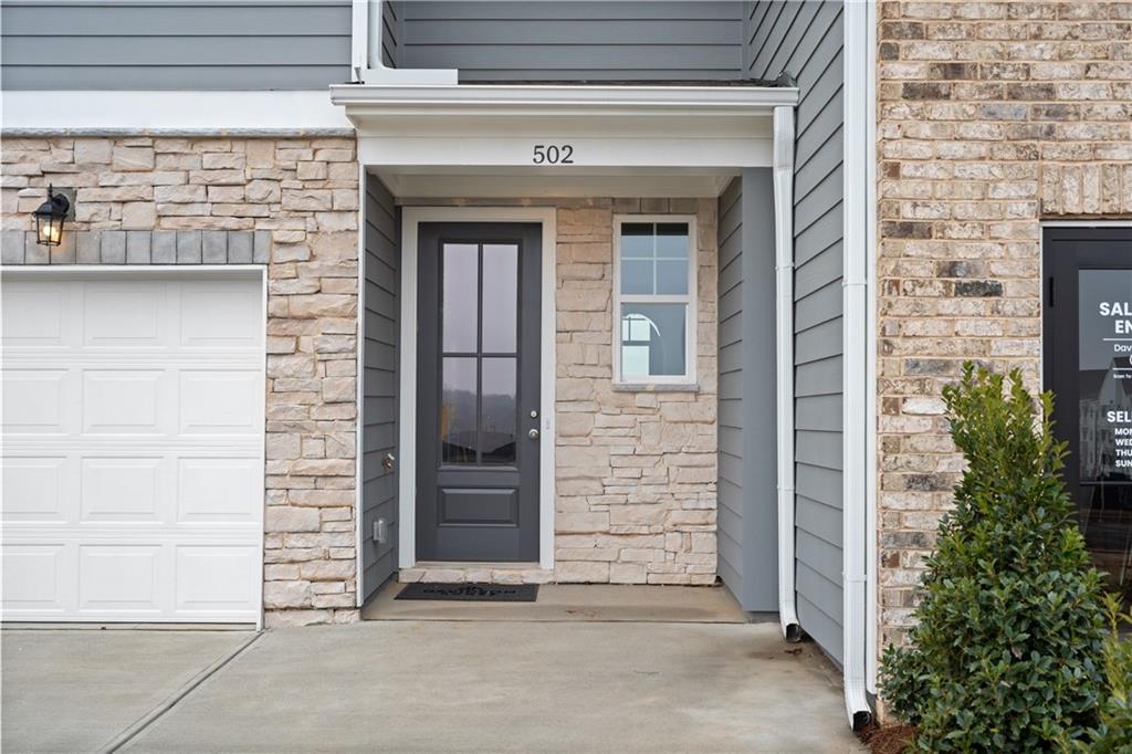 Modern two-story home front with gray siding, stone accents, white garage, and glass-paneled door at 502 in Stegall Village, Emerson, GA by Davidson Homes