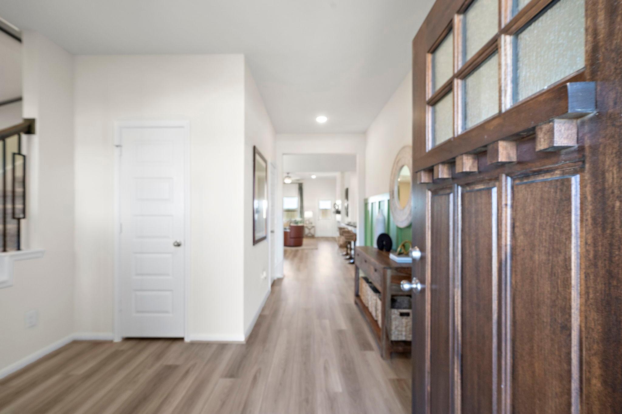 Spacious entryway hallway at River Ranch Meadows in Dayton Texas with wood-look floors, console table, and open living area